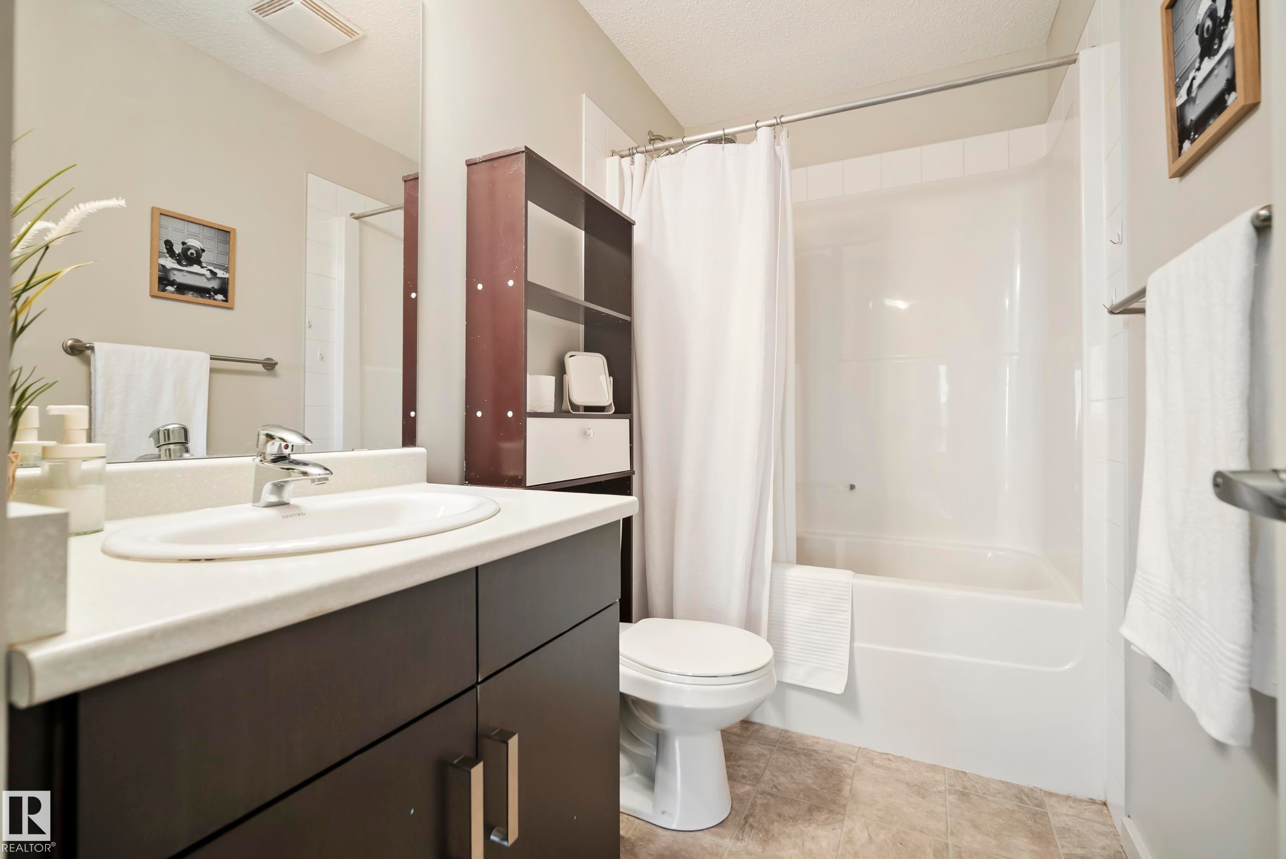 Bathroom featuring a white vanity countertop, undermount sink, dark wood-finish cabinetry, a built-in shower/tub combination, and tiled flooring - #419 5515 7 Av Sw, Edmonton, AB