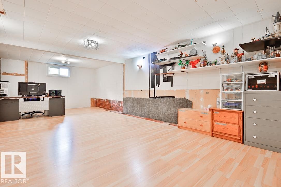 Light wood-finish flooring, drop ceiling with recessed lighting, and wall-mounted shelving units - 13312 123A Street Nw, Edmonton, AB