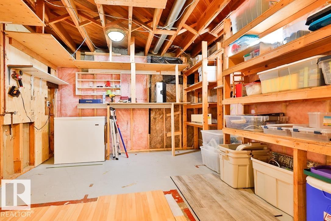 Unfinished basement space featuring exposed wood framing, wood-finish shelving, and concrete flooring - 13312 123A Street Nw, Edmonton, AB