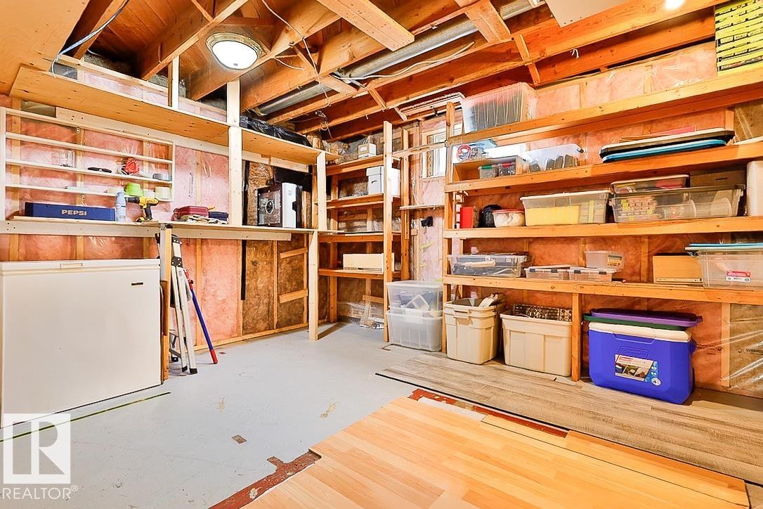 Unfinished basement space with exposed wood framing, comprehensive built-in shelving, and a concrete floor - 13312 123A Street Nw, Edmonton, AB