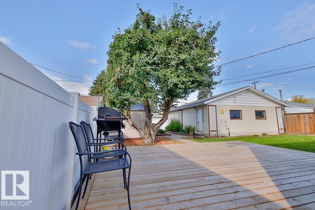 Expansive wood-plank deck with a white privacy fence and mature tree - 13312 123A Street Nw, Edmonton, AB