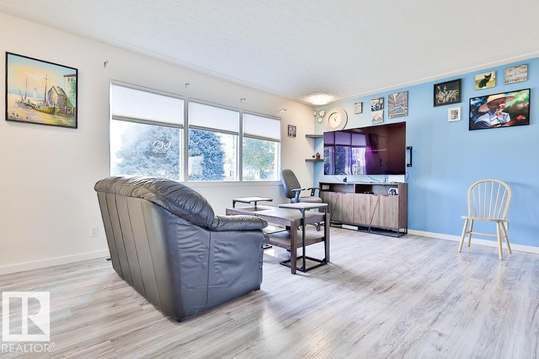 Wood-finish flooring throughout, bright white walls, and a light blue accent wall - 13312 123A Street Nw, Edmonton, AB