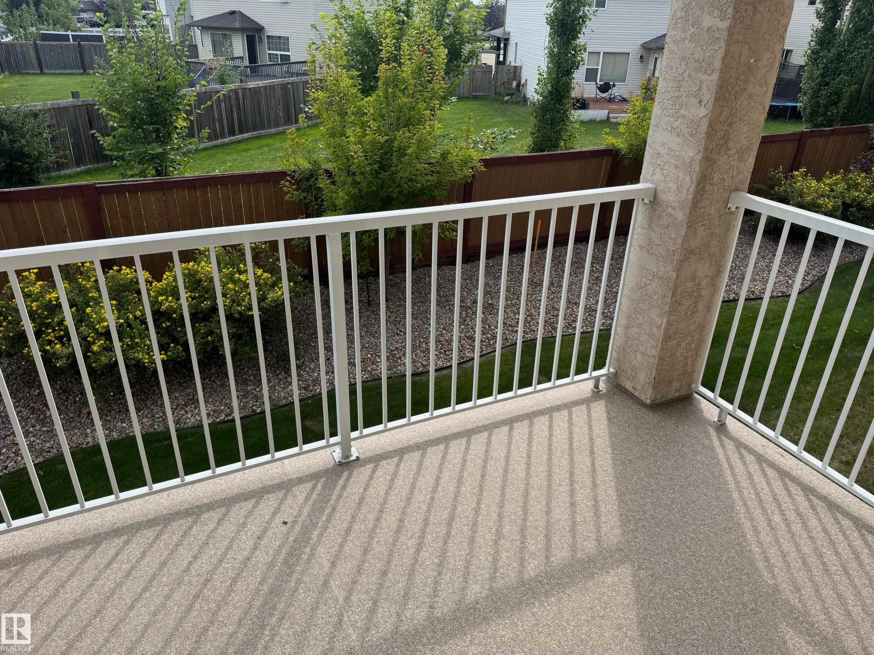 Balcony featuring a textured floor, white metal railing, and a stucco-finished support column - #229 2305 35A Av Nw, Edmonton, AB