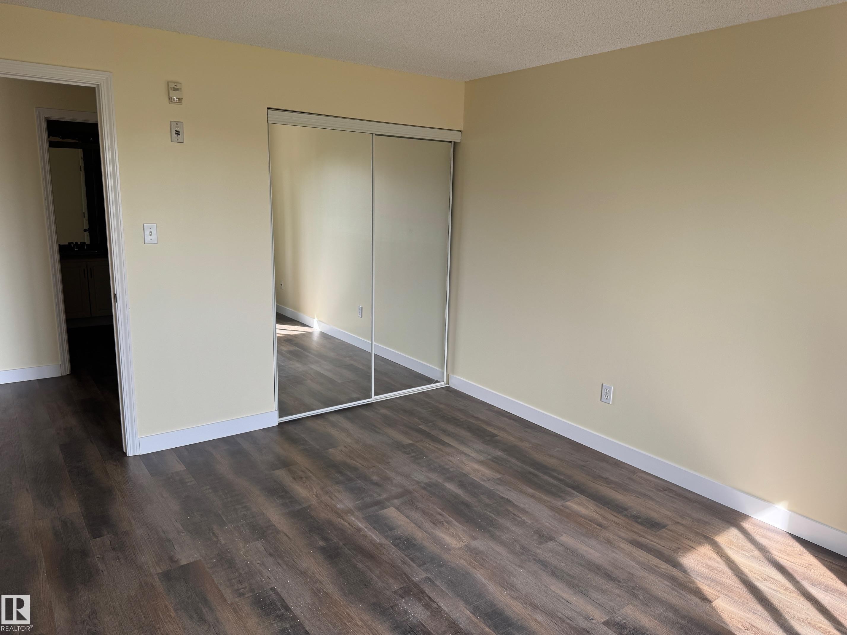 Wood-finish flooring with light-toned walls and mirrored closet doors - #229 2305 35A Av Nw, Edmonton, AB