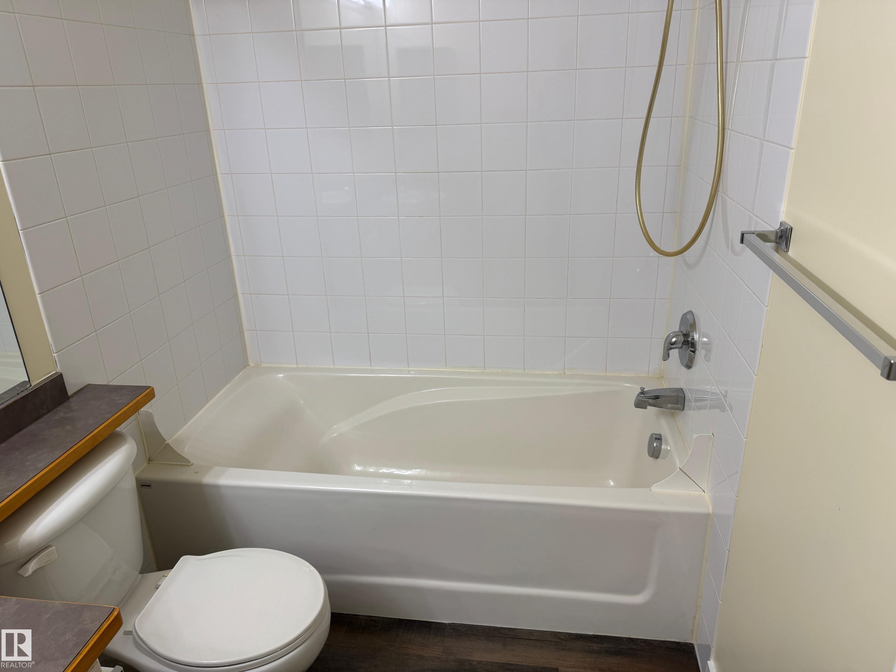 White tile shower surround with a built-in bathtub and chrome fixtures - #229 2305 35A Av Nw, Edmonton, AB