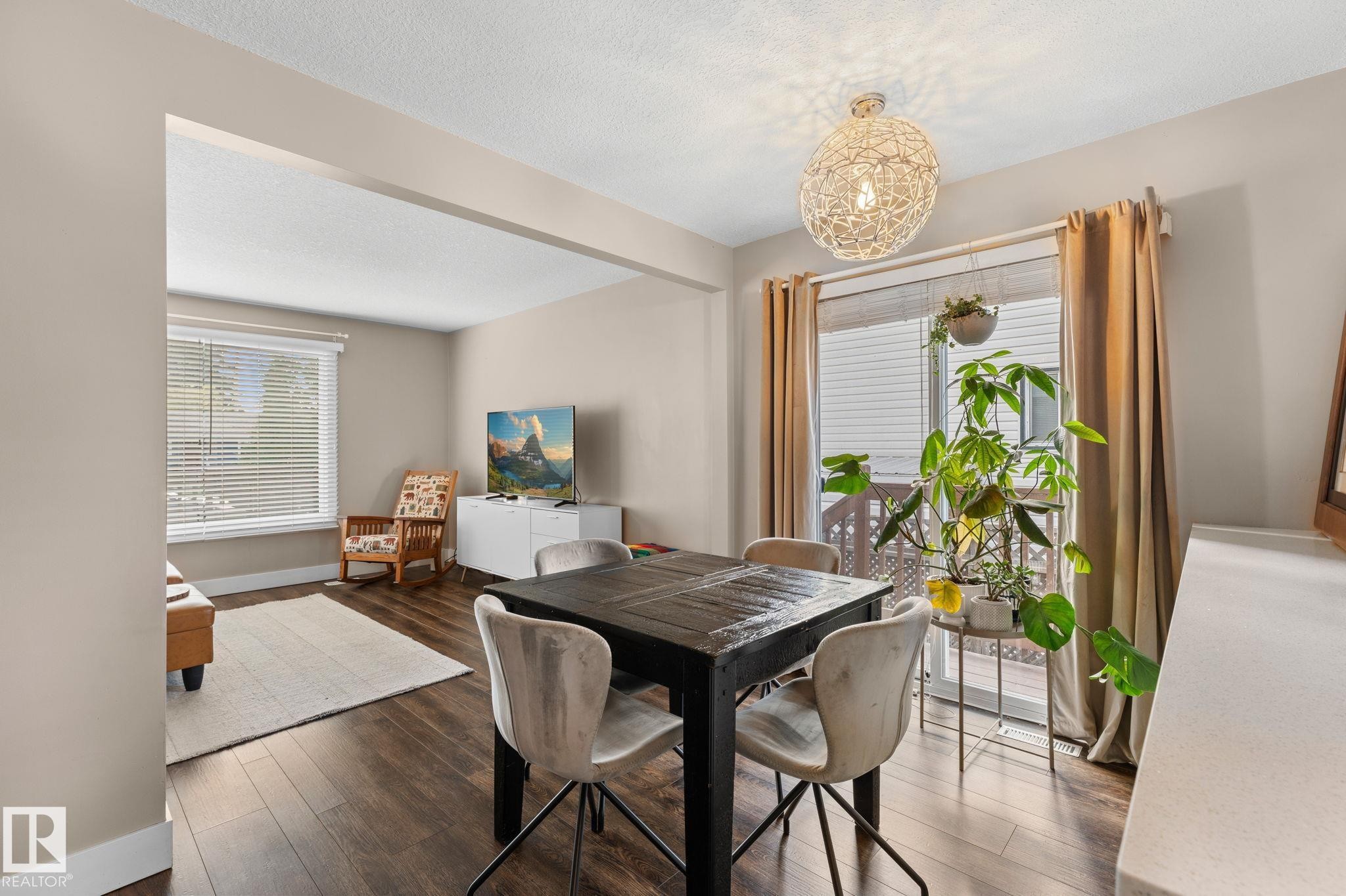 Laminate flooring throughout, with a dining area featuring a pendant light fixture and direct outdoor access via sliding glass doors - 6108 102 Avenue Nw, Edmonton, AB