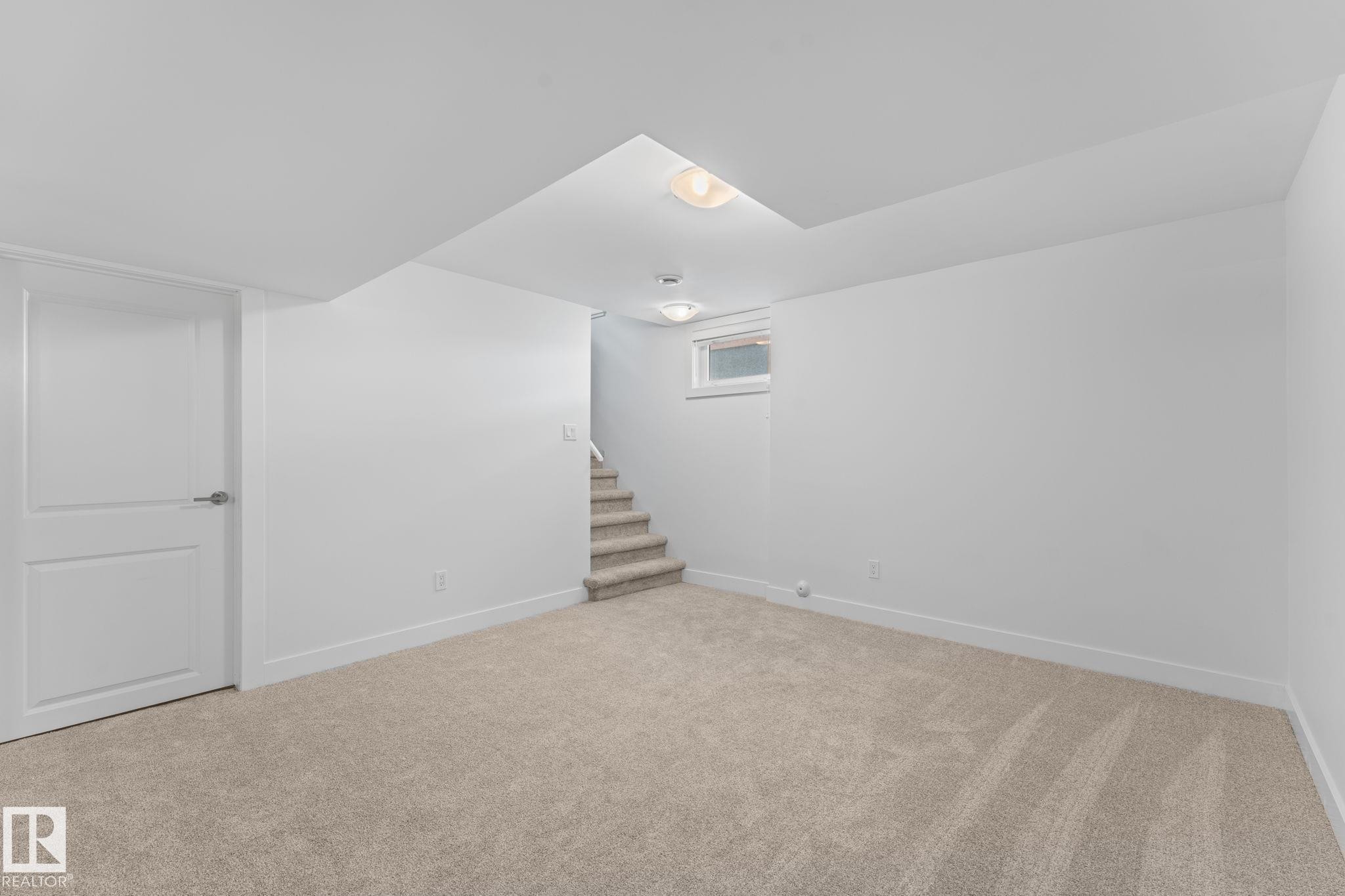 Neutral paint colors with ceiling mounted lighting, plush carpeting, and wood-finish flooring, and a visible window - 6108 102 Avenue Nw, Edmonton, AB