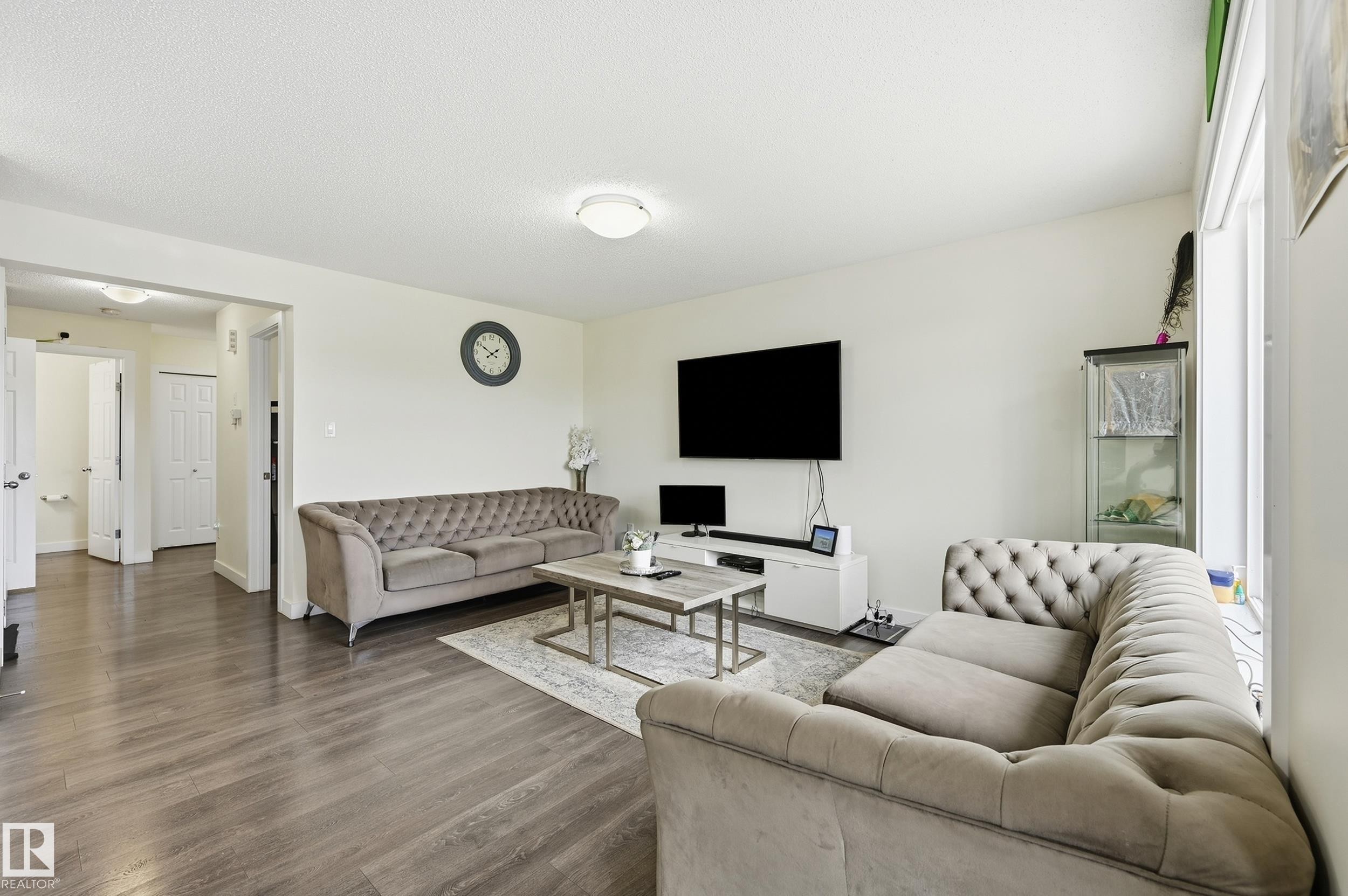 Spacious living area featuring wood-finish flooring, light-colored walls, and a ceiling-mounted light fixture - 941 Ebbers Crescent Nw, Edmonton, AB