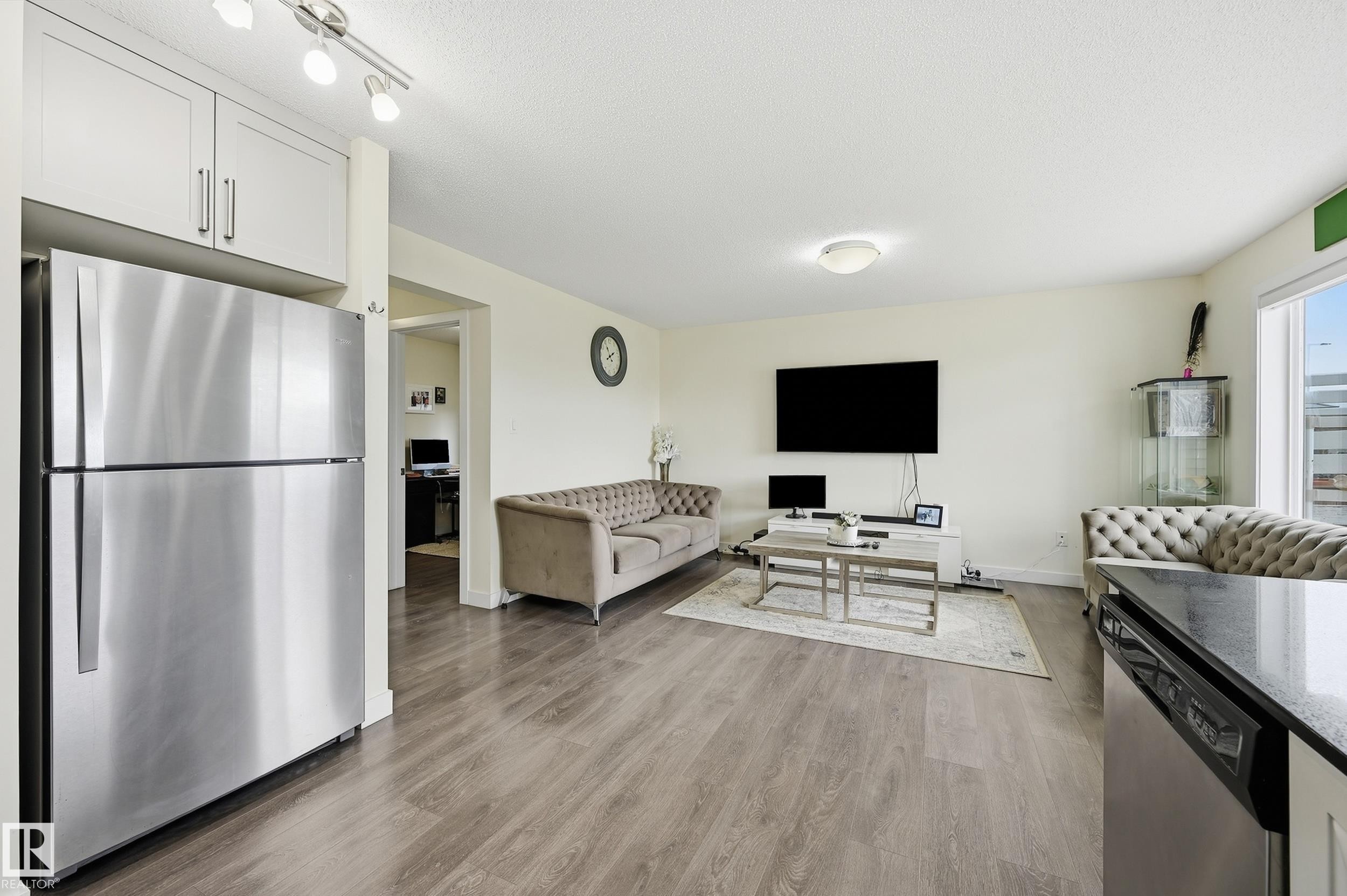 Stainless steel refrigerator, light-toned upper cabinetry, wood-finish flooring, white walls, and a large window - 941 Ebbers Crescent Nw, Edmonton, AB