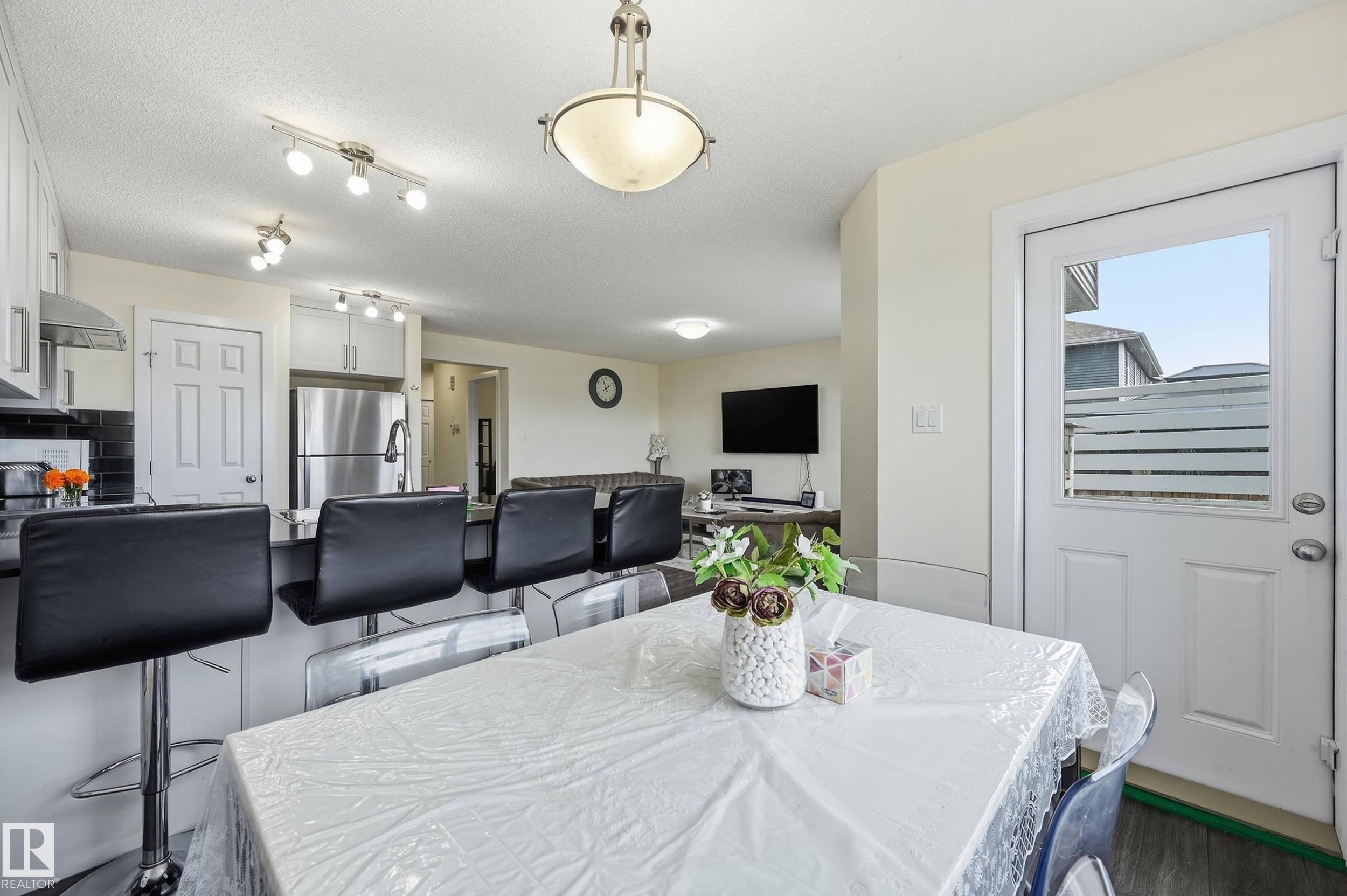 Kitchen with white cabinetry, stainless steel appliances, black countertops, and track lighting - 941 Ebbers Crescent Nw, Edmonton, AB
