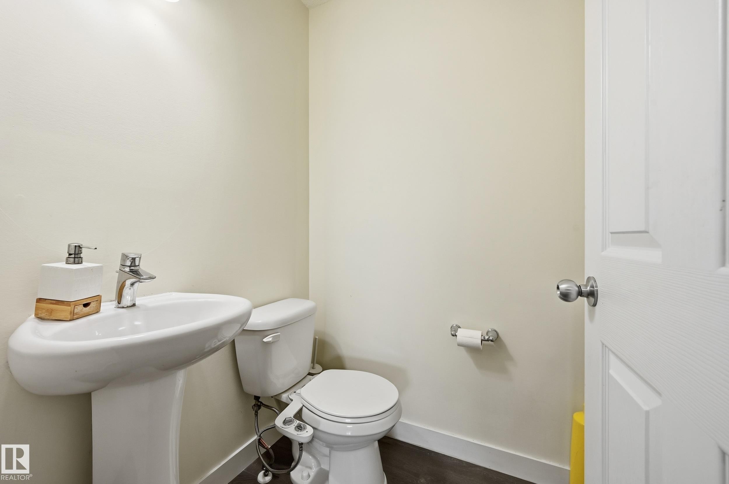Pedestal sink with chrome-finish faucet, white toilet, and wood-finish flooring - 941 Ebbers Crescent Nw, Edmonton, AB