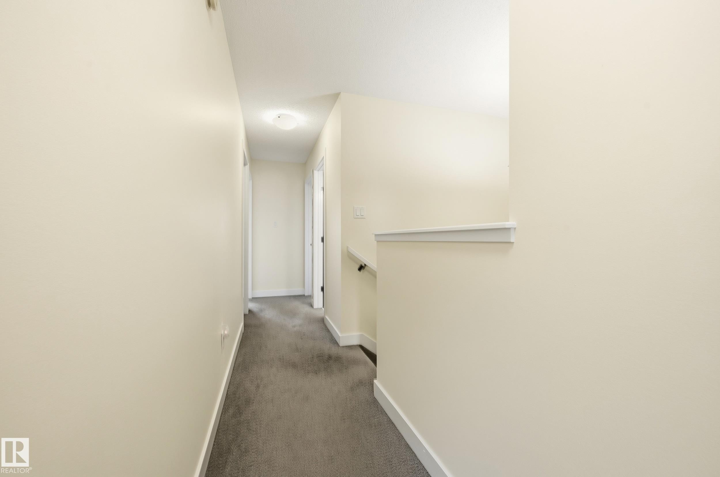 Hallway with neutral wall tones and dark carpeting - 941 Ebbers Crescent Nw, Edmonton, AB