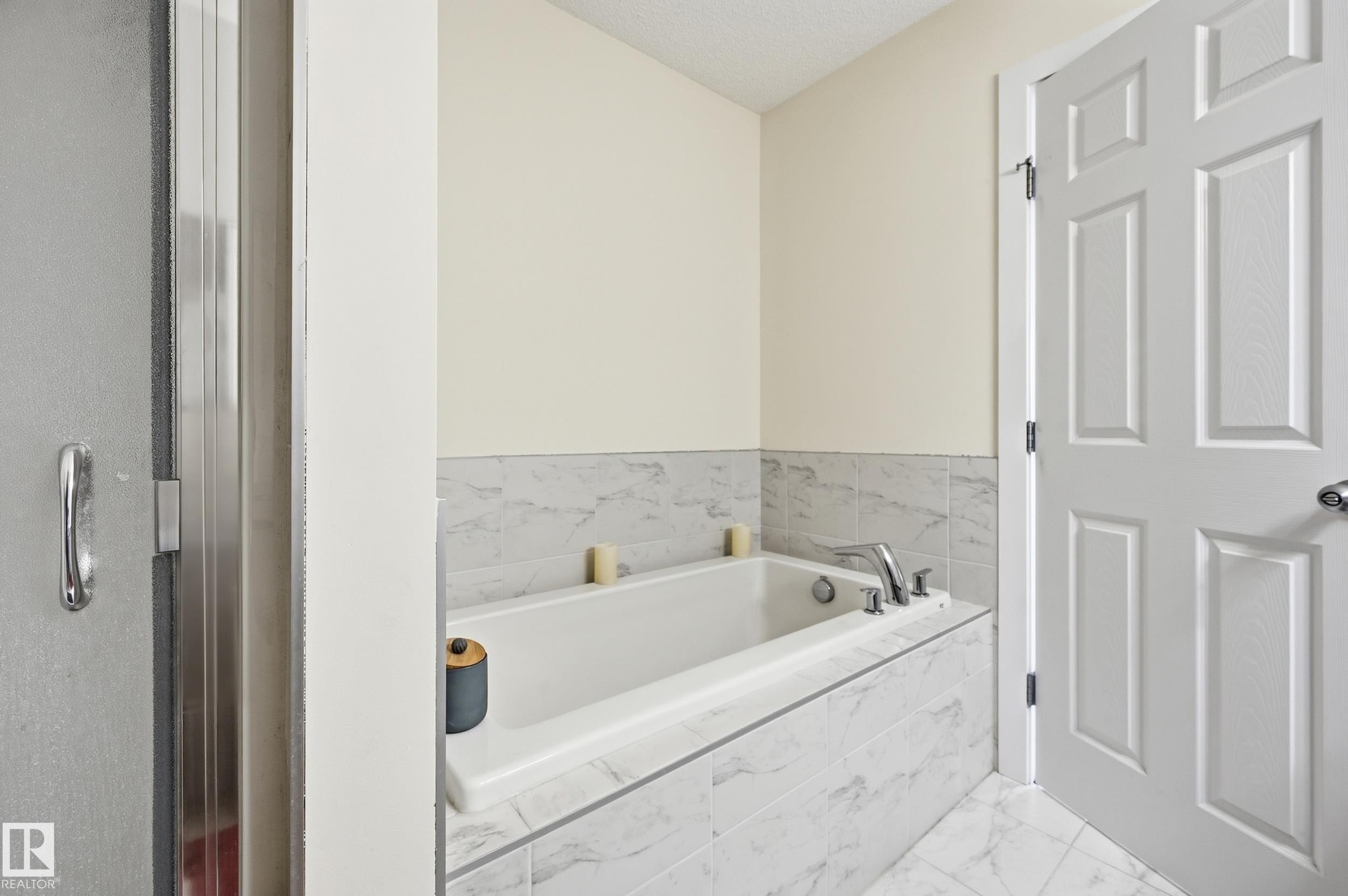 Built-in bathtub with tiled surround, chrome fixtures, and complementary tiled flooring - 941 Ebbers Crescent Nw, Edmonton, AB
