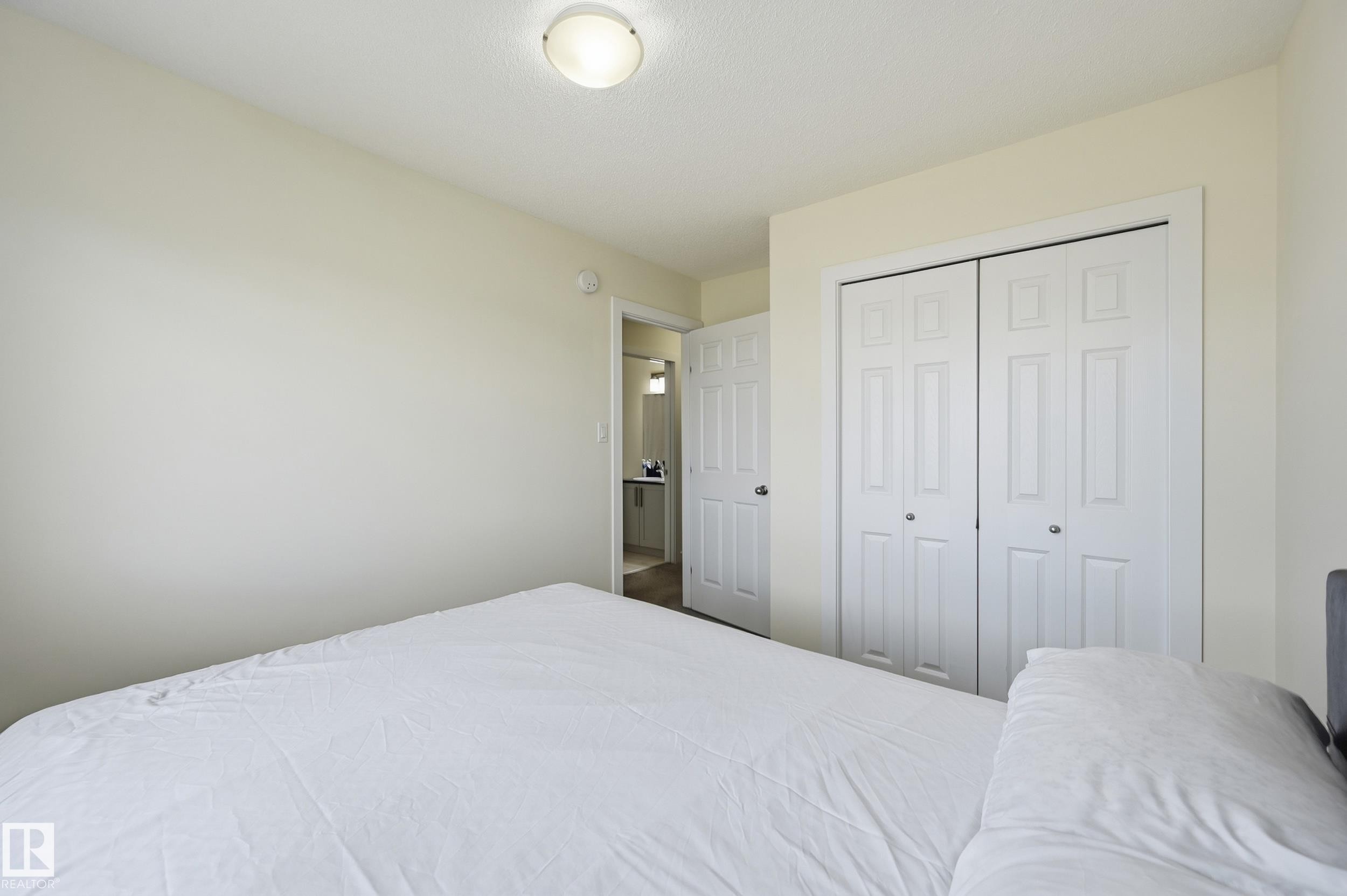 White bi-fold closet doors, flush-mount ceiling light, and light-toned wall paint - 941 Ebbers Crescent Nw, Edmonton, AB