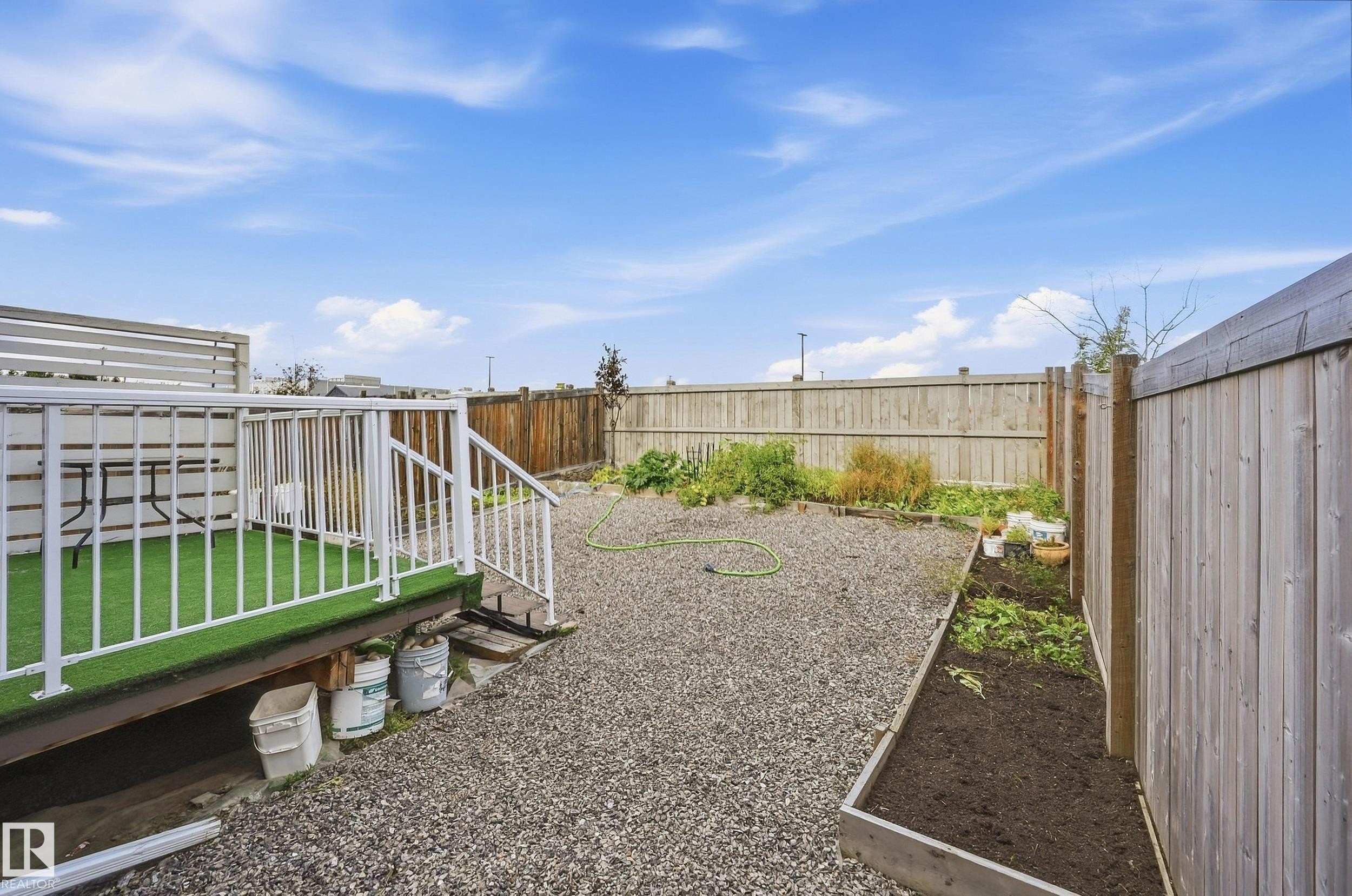 Elevated deck with white railing, artificial turf surface, and slatted privacy screen - 941 Ebbers Crescent Nw, Edmonton, AB