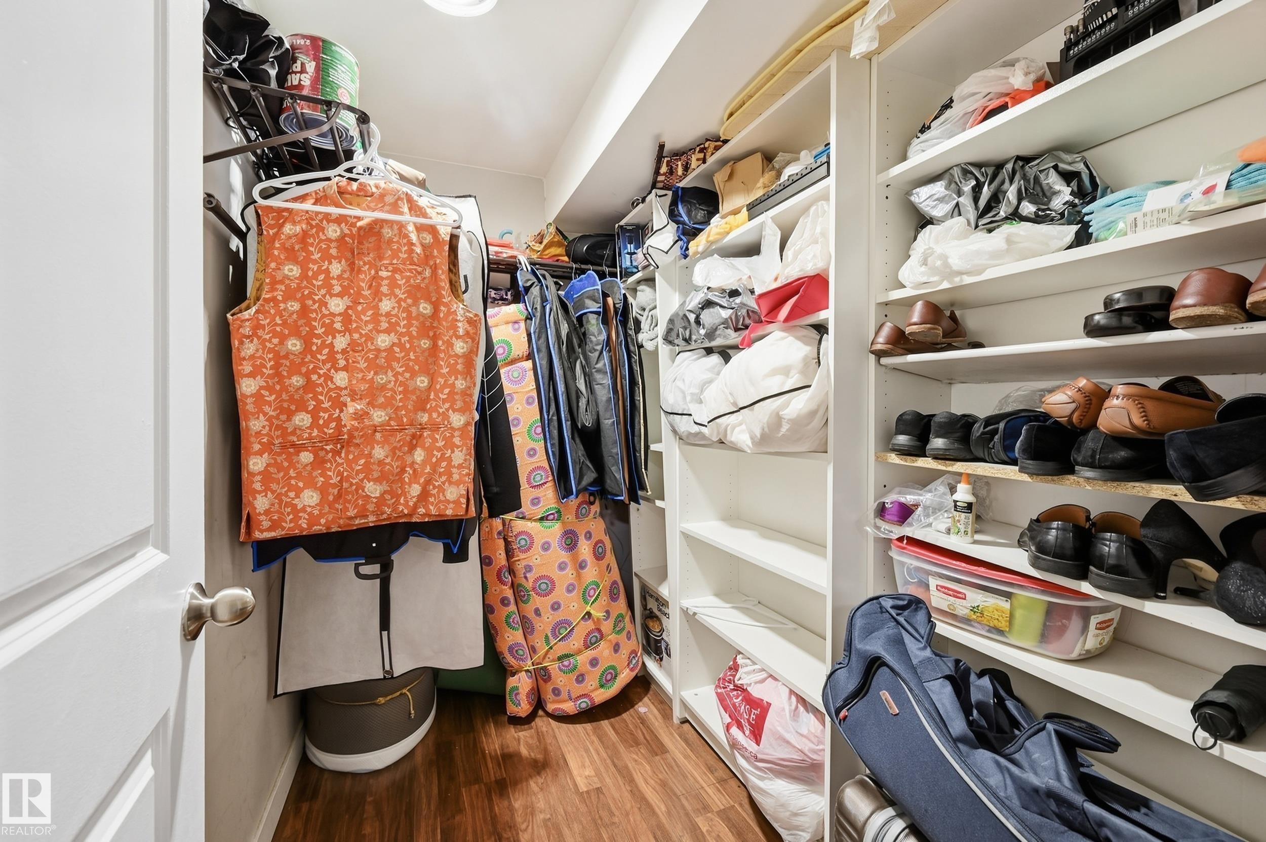 Walk-in closet featuring wood-finish flooring, white shelving, and hanging storage - 941 Ebbers Crescent Nw, Edmonton, AB
