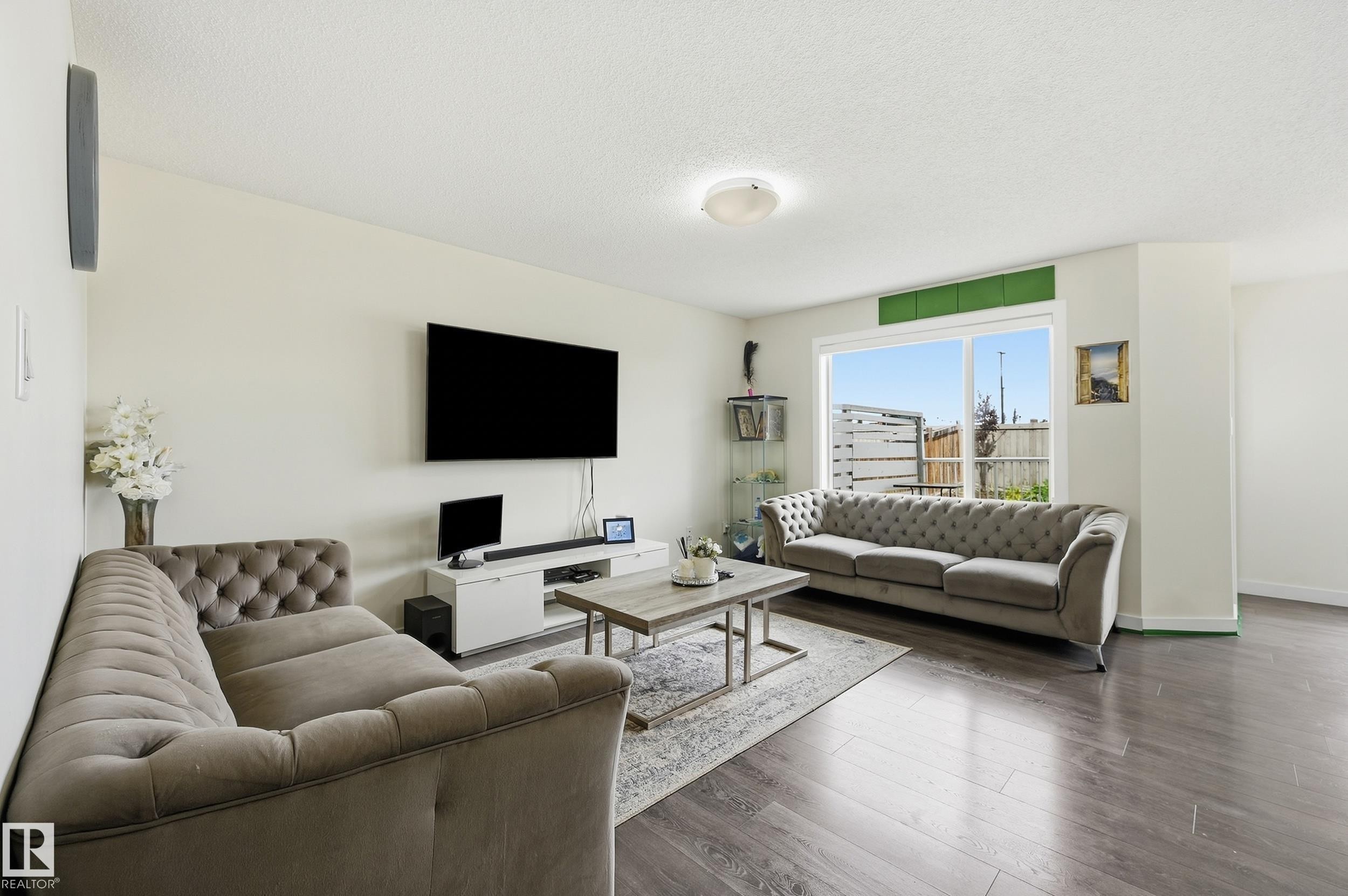 Spacious living area featuring wood-finish flooring, a large window, and light-toned walls - 941 Ebbers Crescent Nw, Edmonton, AB