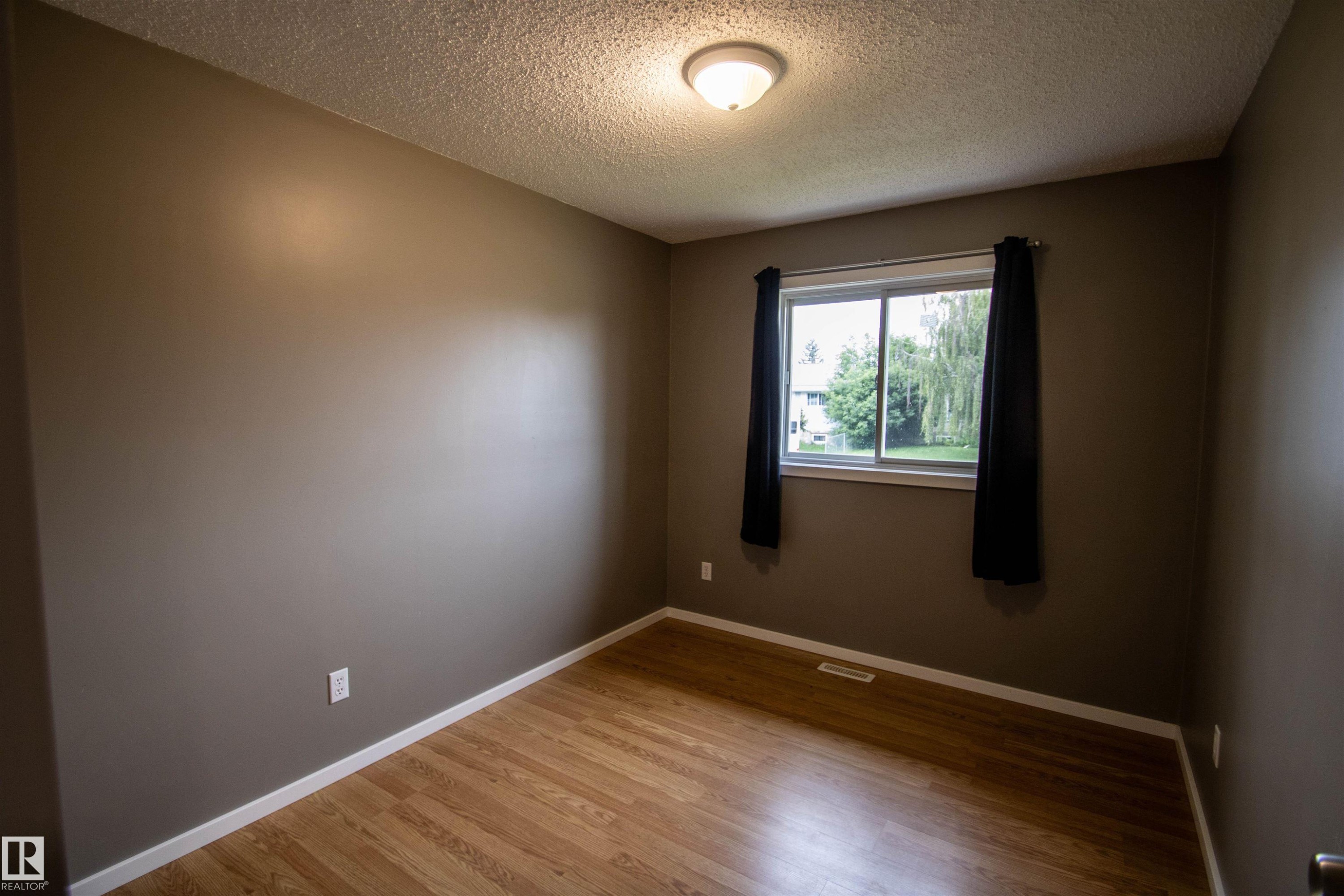 Room featuring wood-finish flooring, a double-paned window, and a flush-mount ceiling light - 4725 45 Ave, St. Paul Town, AB - Indoor Photo Showing Other Room