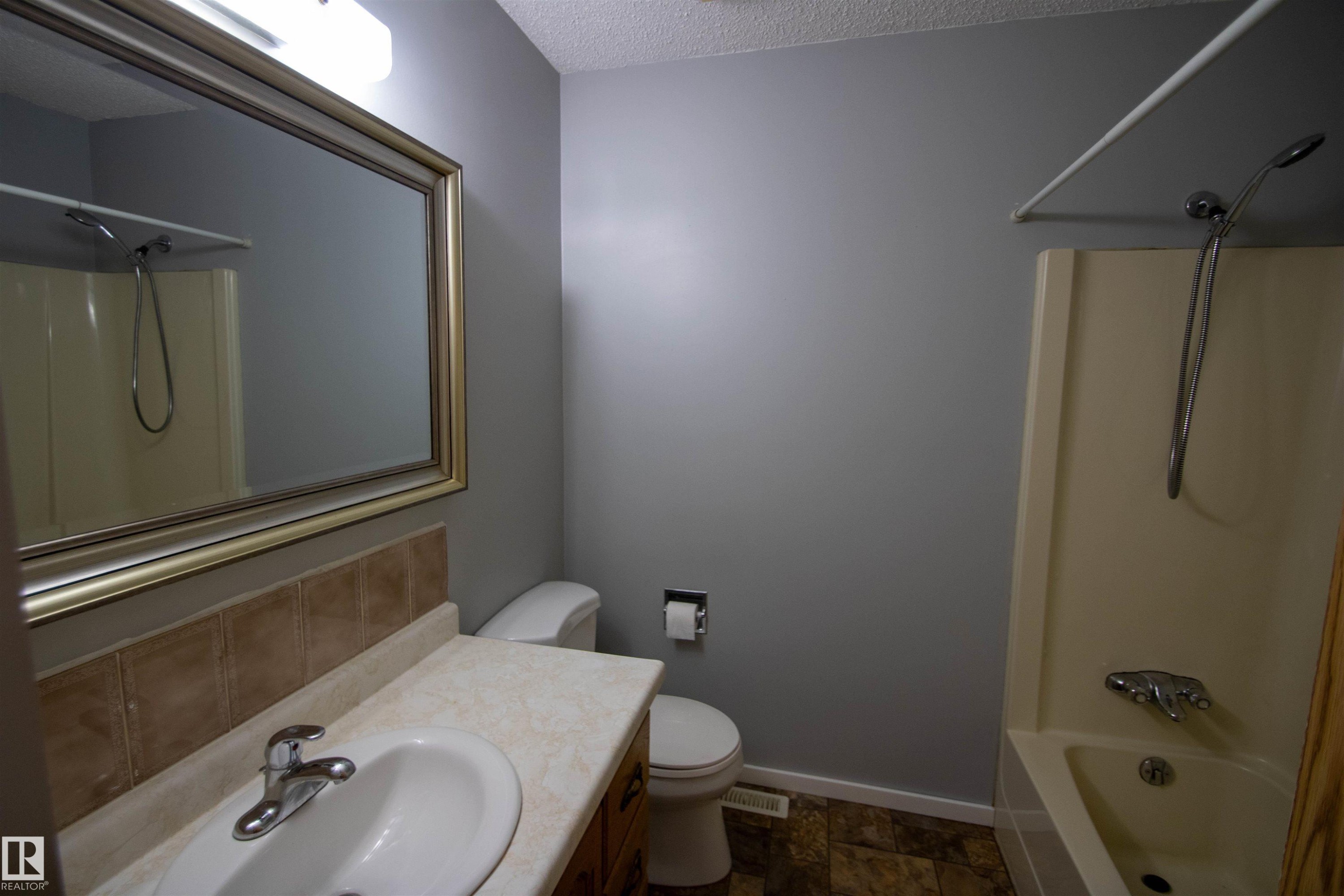 Bathroom featuring a vanity with a white basin sink, polished chrome faucet, and a large framed mirror - 4725 45 Ave, St. Paul Town, AB - Indoor Photo Showing Bathroom
