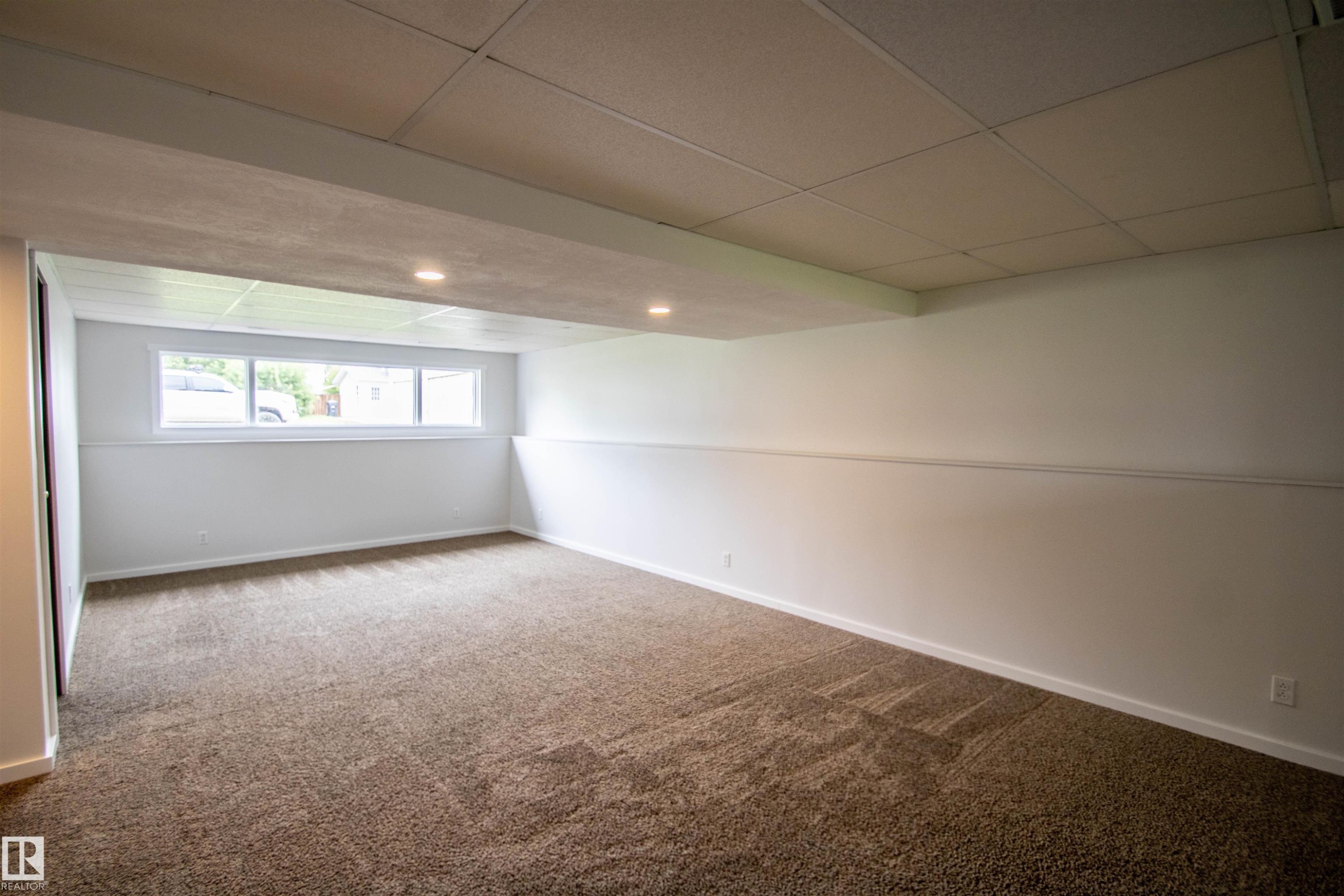 Carpeted interior space with a dropped ceiling and recessed lighting - 4725 45 Ave, St. Paul Town, AB - Indoor
