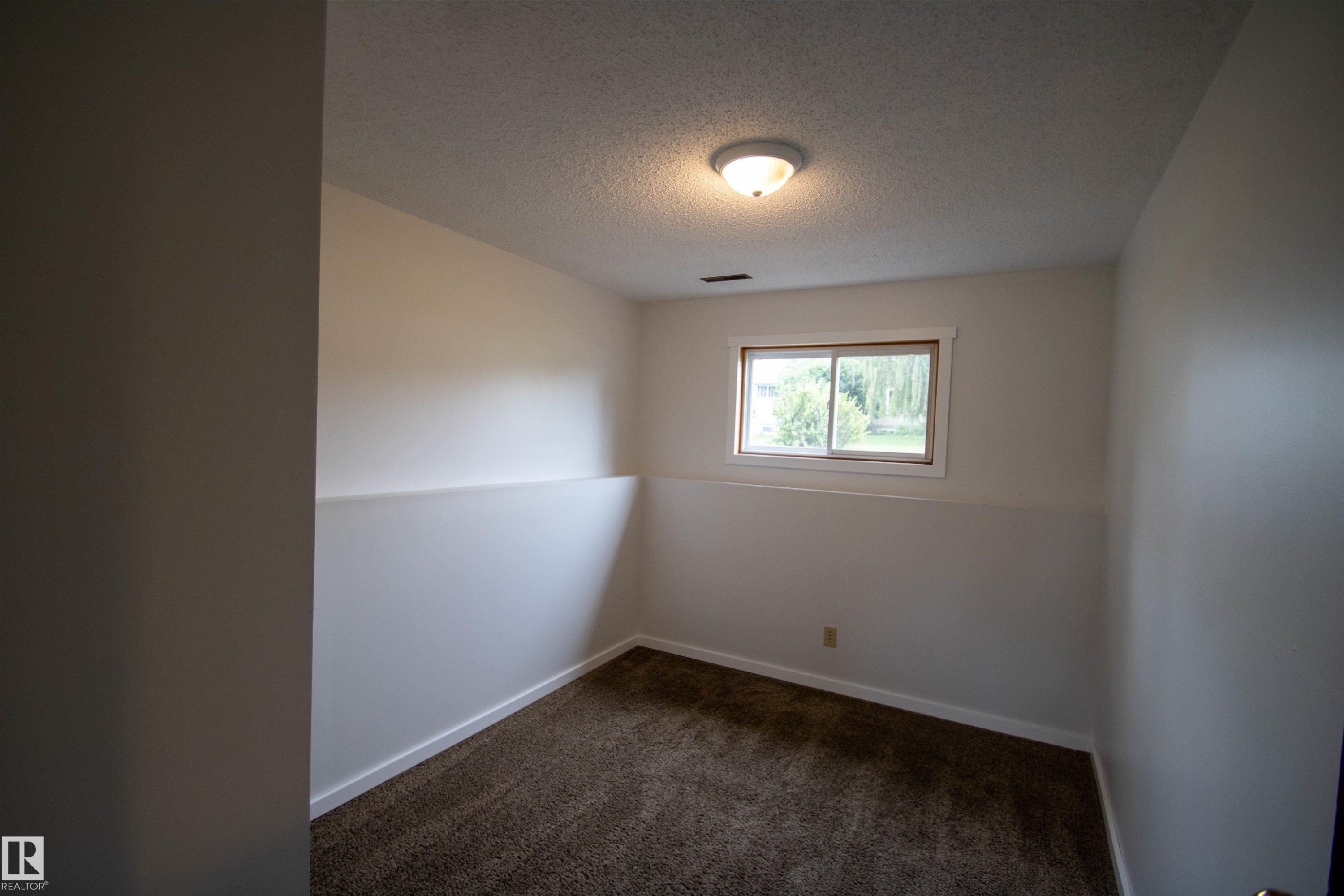 Carpeted interior space with a single window and overhead lighting - 4725 45 Ave, St. Paul Town, AB - Indoor Photo Showing Other Room