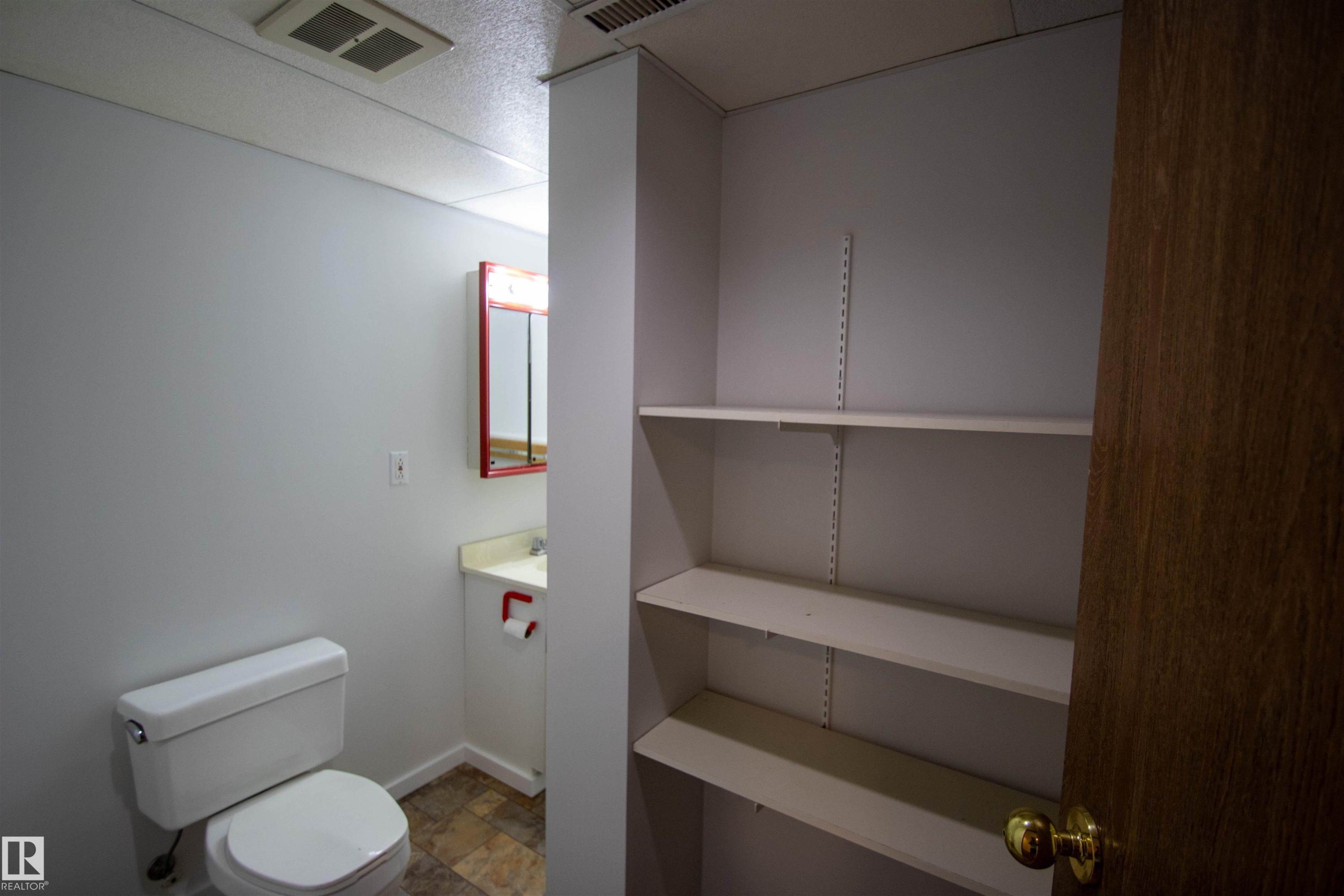 Bathroom featuring a white toilet, single vanity with a laminate countertop, and a red framed medicine cabinet - 4725 45 Ave, St. Paul Town, AB - Indoor Photo Showing Bathroom