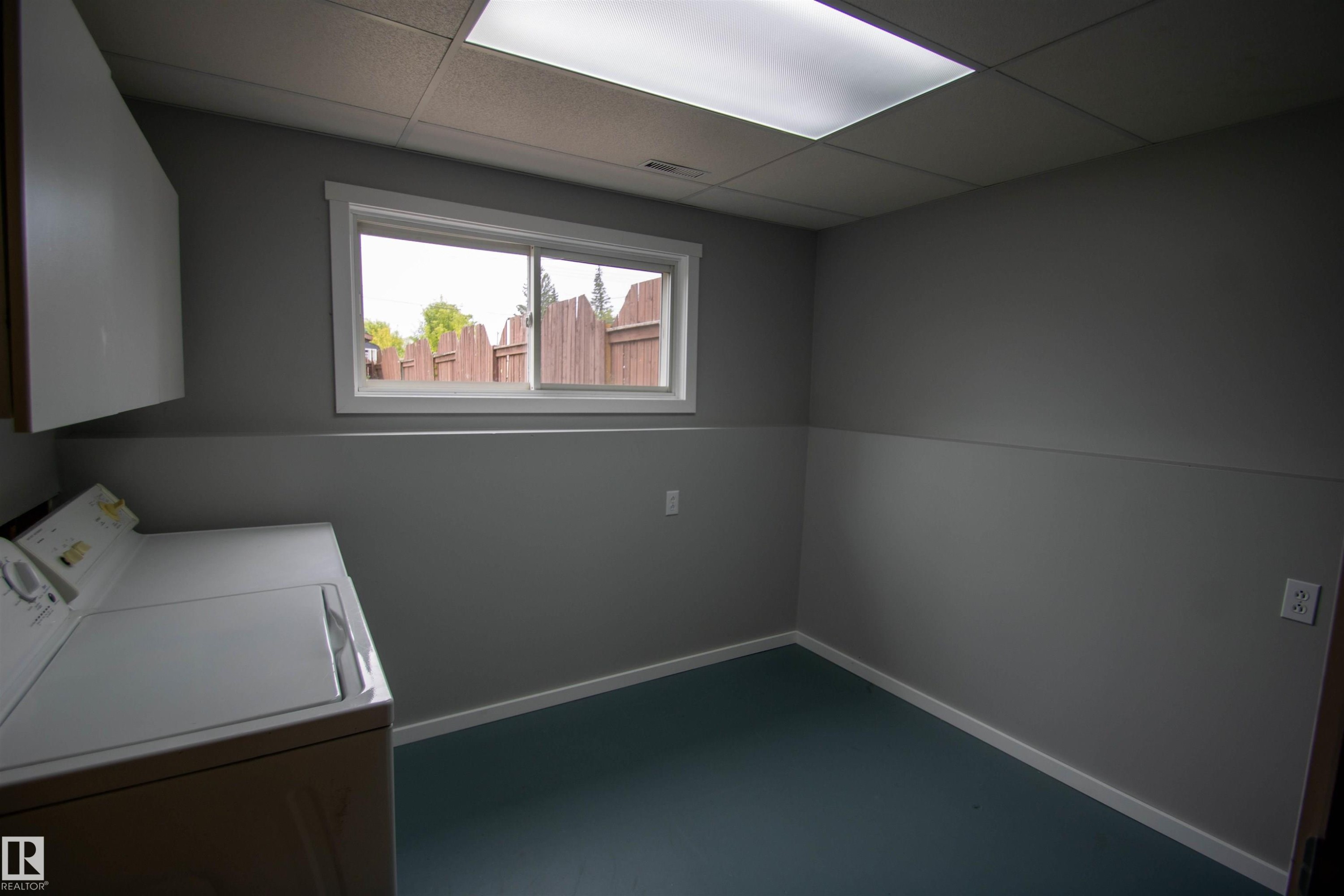 Utility room featuring a sliding window, white trim, recessed overhead lighting, and built-in upper cabinetry - 4725 45 Ave, St. Paul Town, AB - Indoor Photo Showing Laundry Room