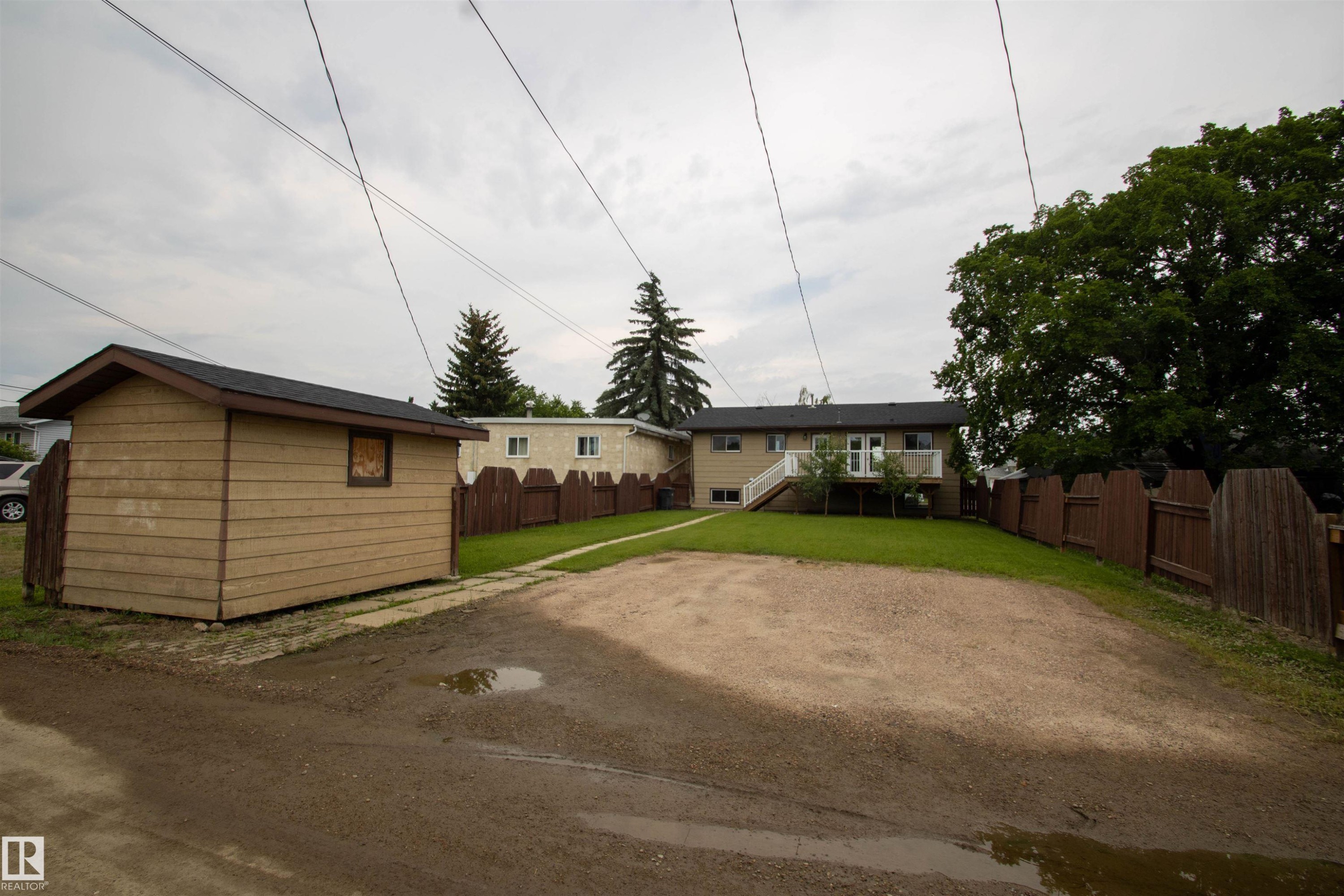 Spacious gravel parking area fronting a detached shed with horizontal siding - 4725 45 Ave, St. Paul Town, AB - Outdoor With Deck Patio Veranda