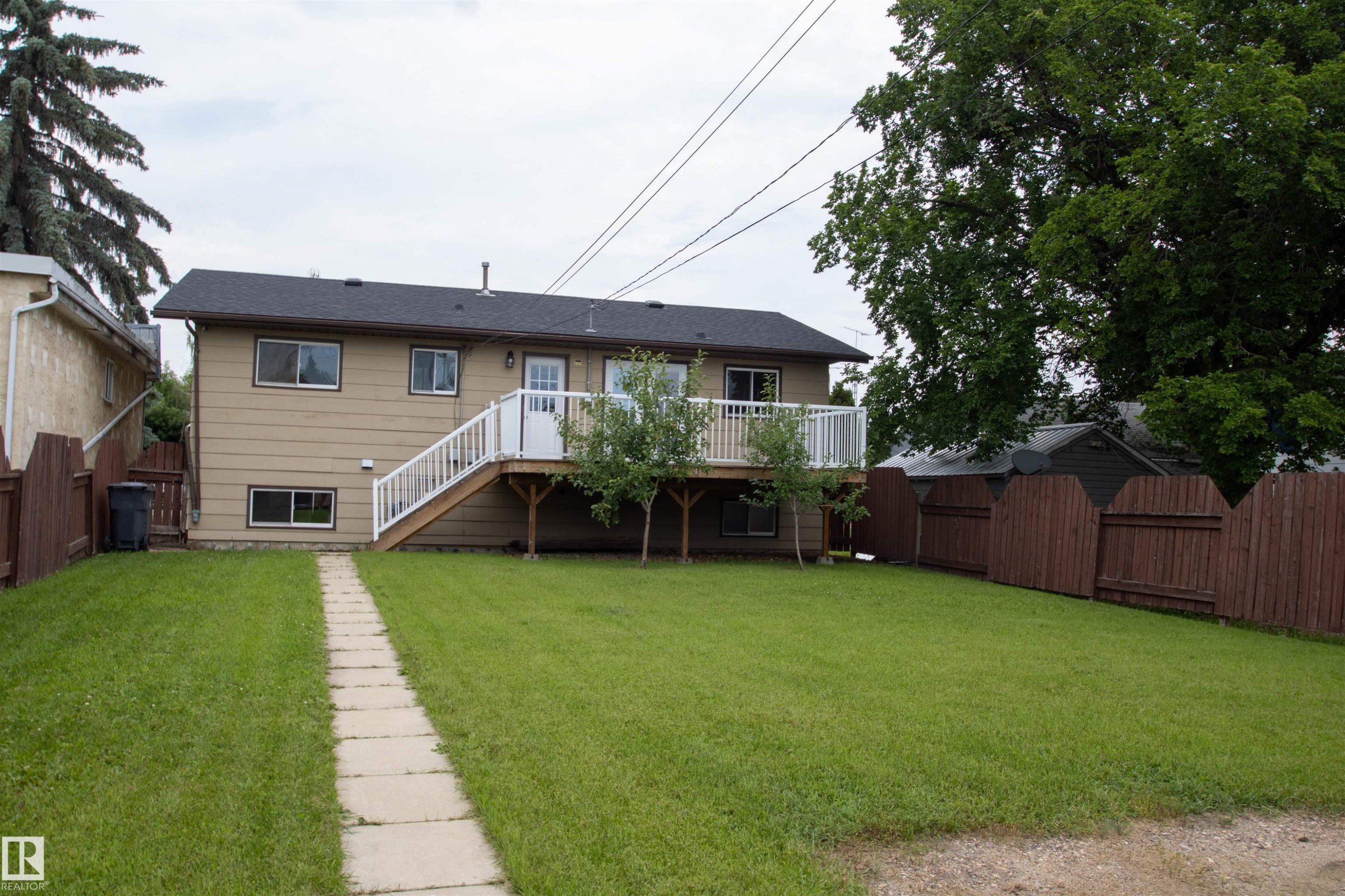 Expansive rear yard featuring a stone pathway, mature trees, and a wooden privacy fence - 4725 45 Ave, St. Paul Town, AB - Outdoor With Deck Patio Veranda