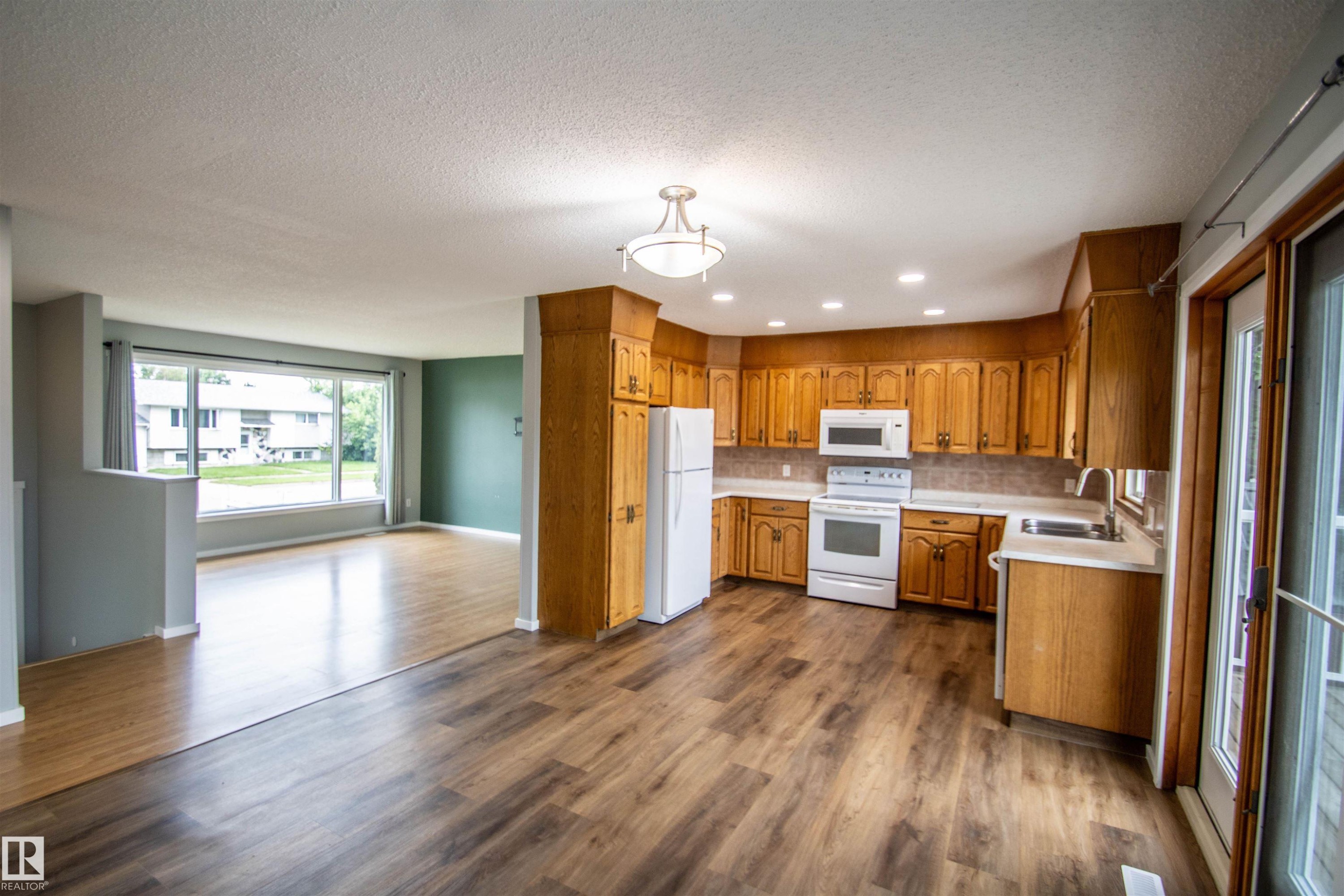 Spacious kitchen featuring wood cabinetry, white appliances, and a light-toned backsplash - 4725 45 Ave, St. Paul Town, AB - Indoor Photo Showing Kitchen