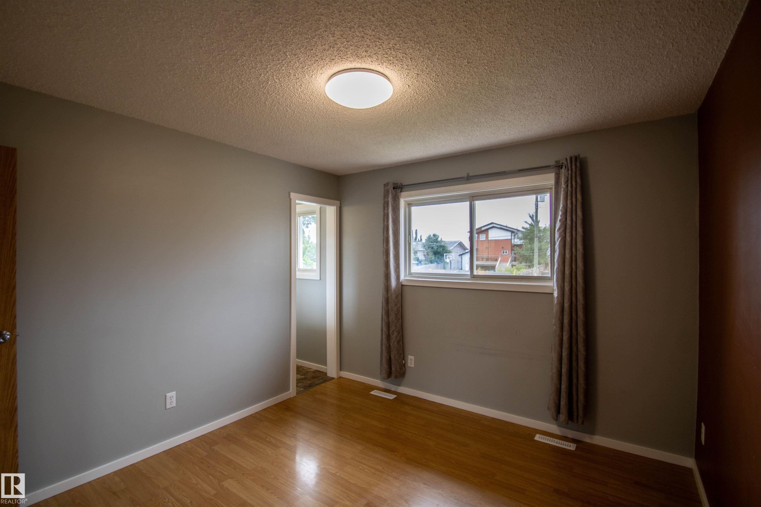 Room featuring wood-finish flooring, a neutral paint palette, and a flush-mount ceiling light fixture - 4725 45 Ave, St. Paul Town, AB - Indoor Photo Showing Other Room