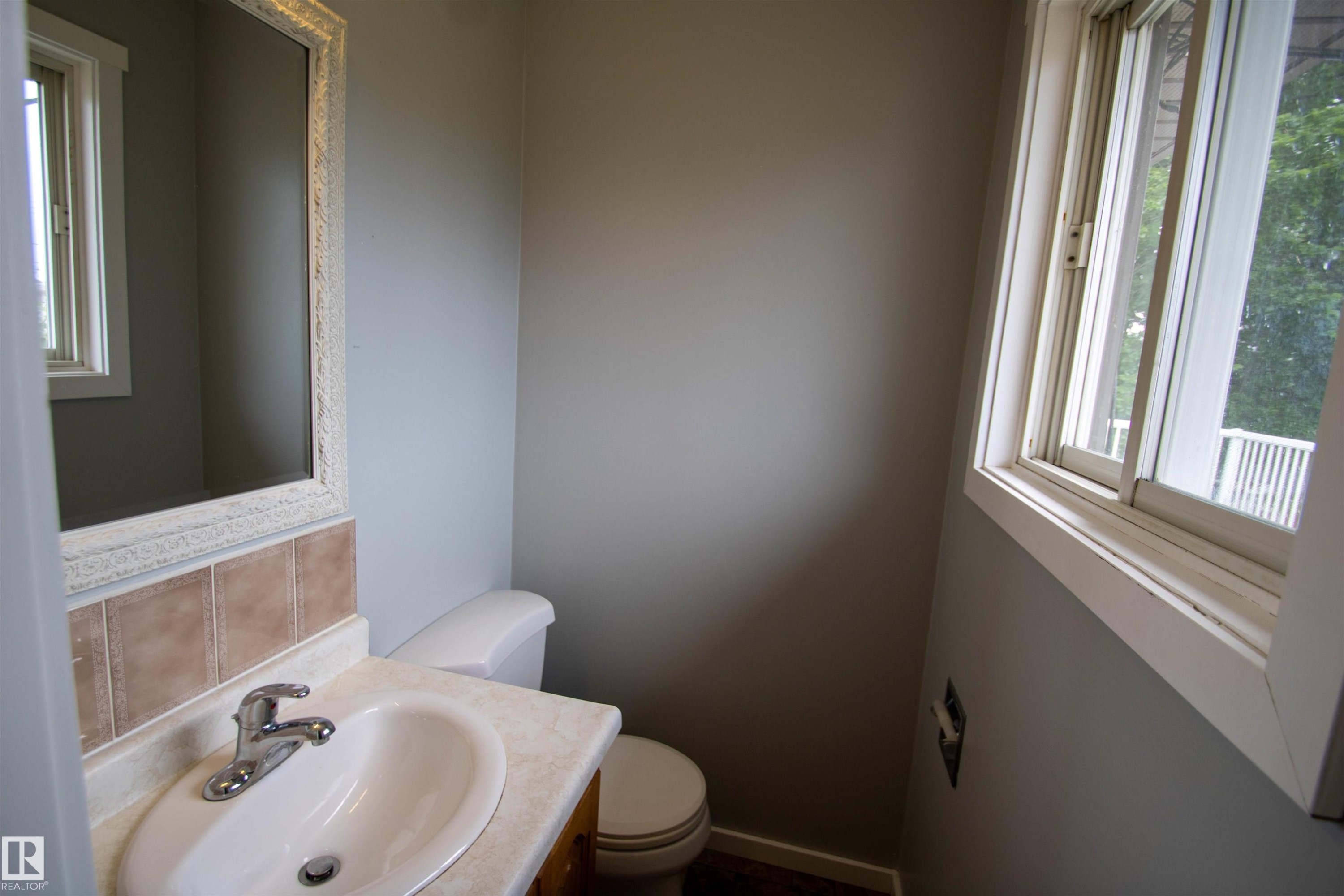 Bathroom vanity with a chrome faucet, oval undermount sink, and light-toned countertop - 4725 45 Ave, St. Paul Town, AB - Indoor Photo Showing Bathroom