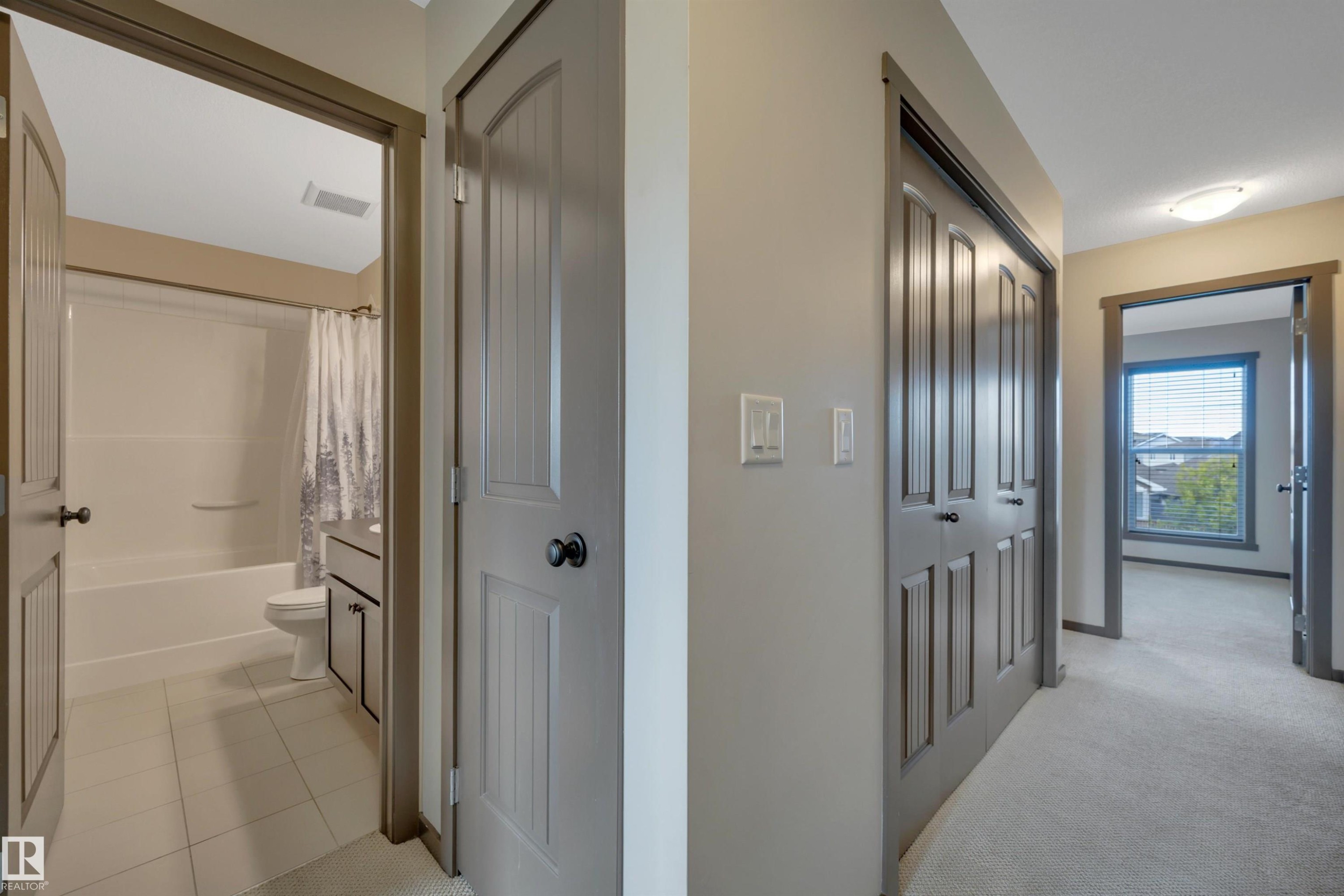 Hallway featuring neutral-toned walls, carpeted flooring, and paneled doors - 12903 205 Street Nw, Edmonton, AB
