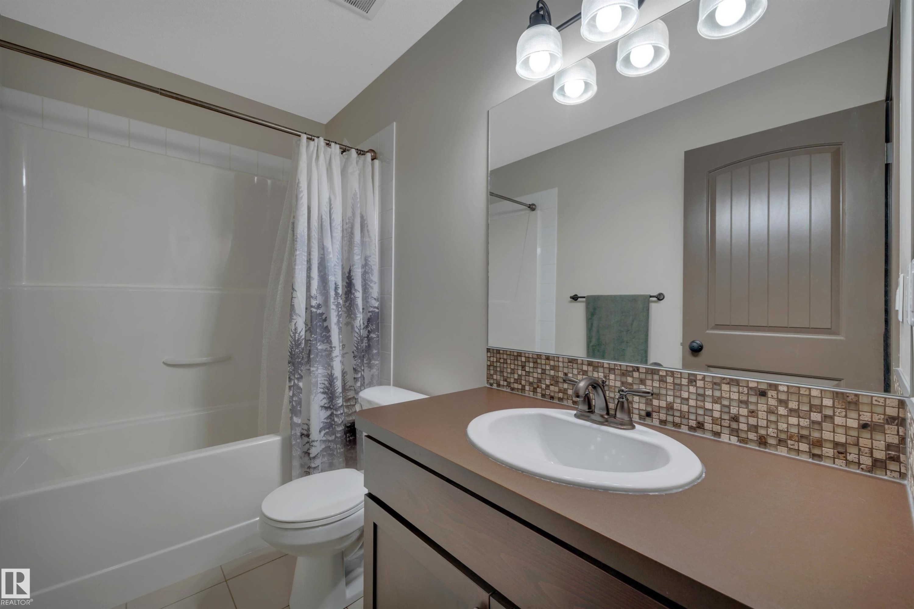 Full vanity mirror, integrated sink, mosaic tile backsplash, and a shower-over-tub combination - 12903 205 Street Nw, Edmonton, AB