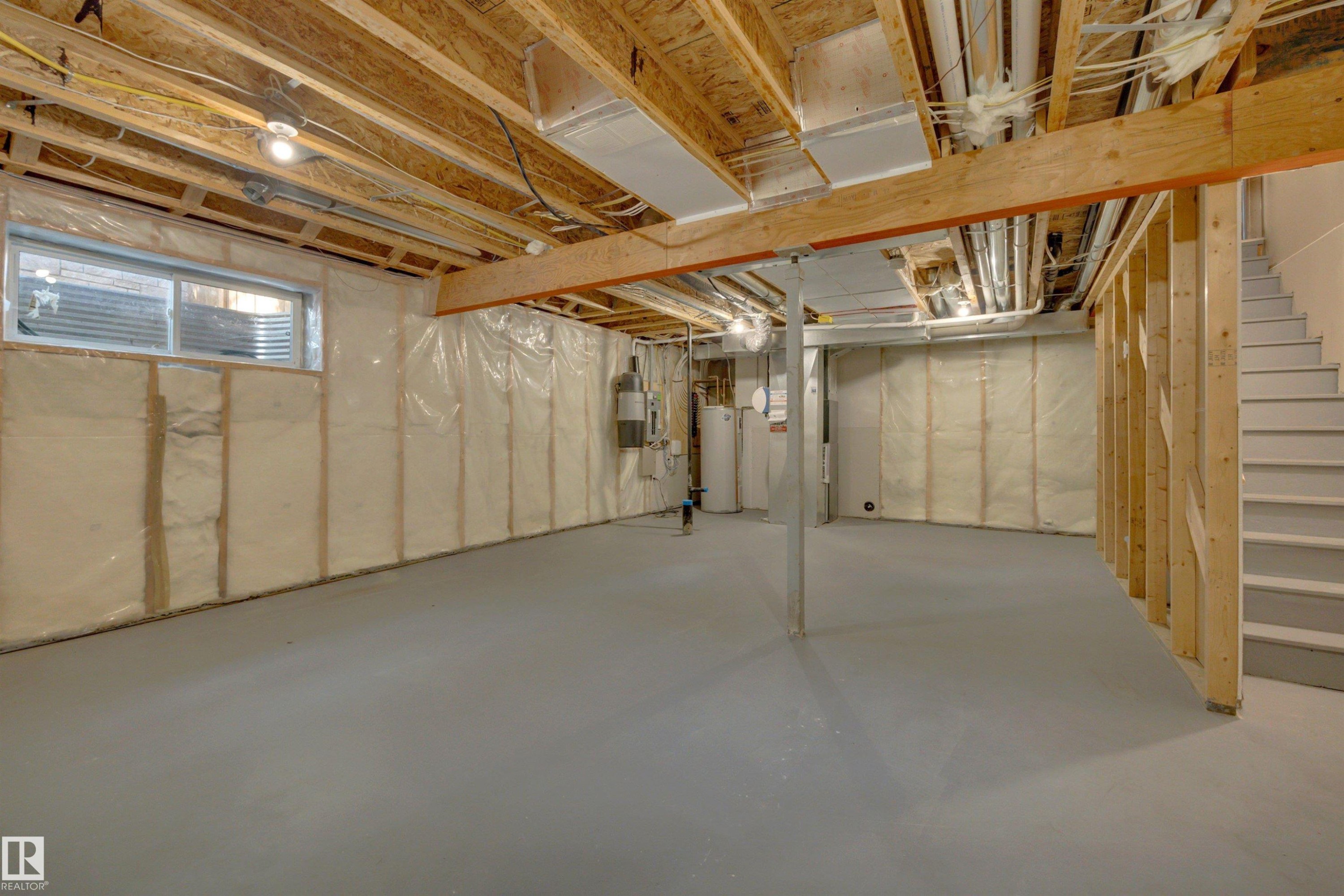 Unfinished basement space featuring exposed wooden joists, framed walls with insulation, a concrete floor, and a utility window - 12903 205 Street Nw, Edmonton, AB
