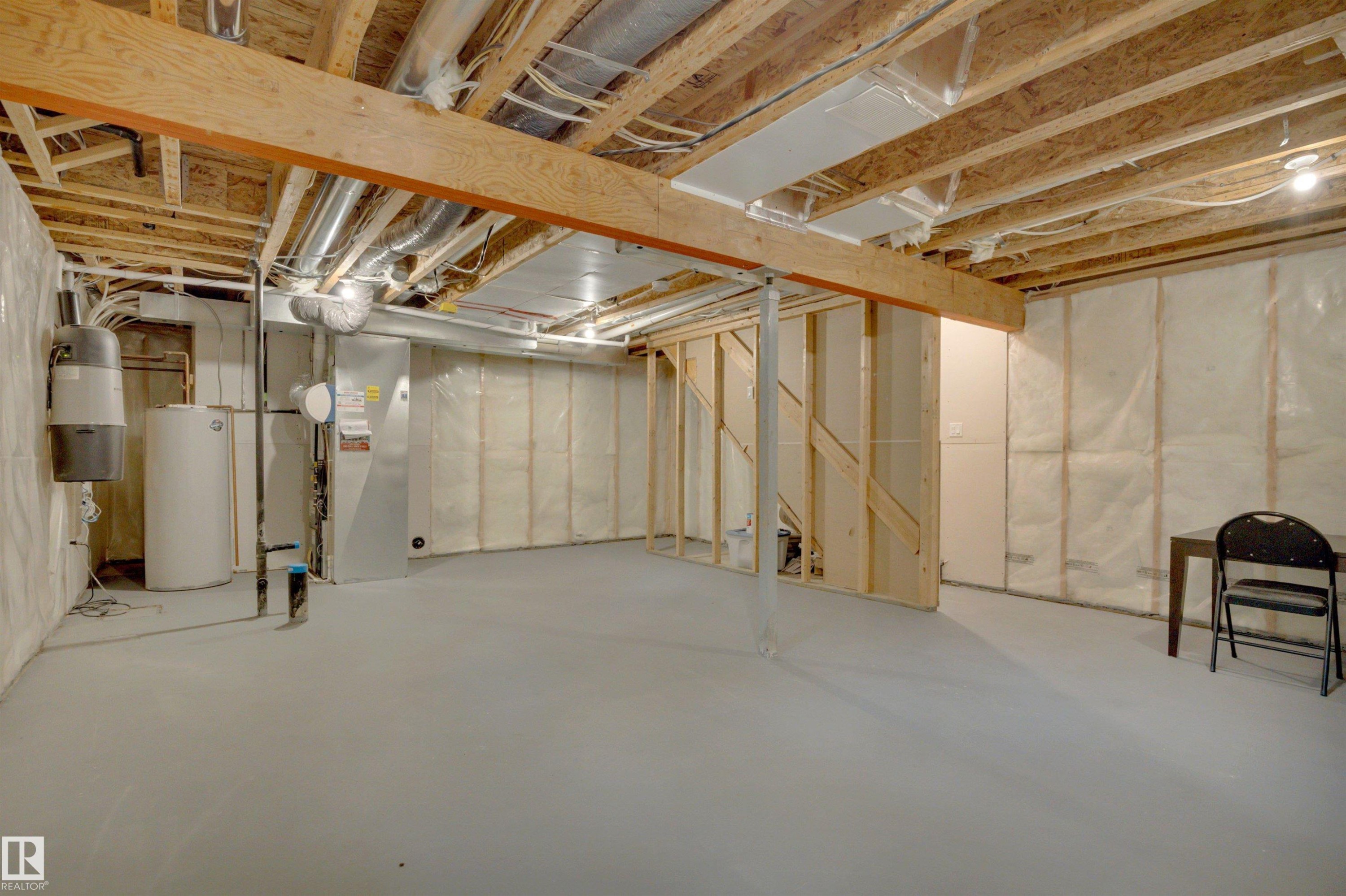 Unfinished basement featuring exposed wood joists, structural wood beams, and a water heater - 12903 205 Street Nw, Edmonton, AB