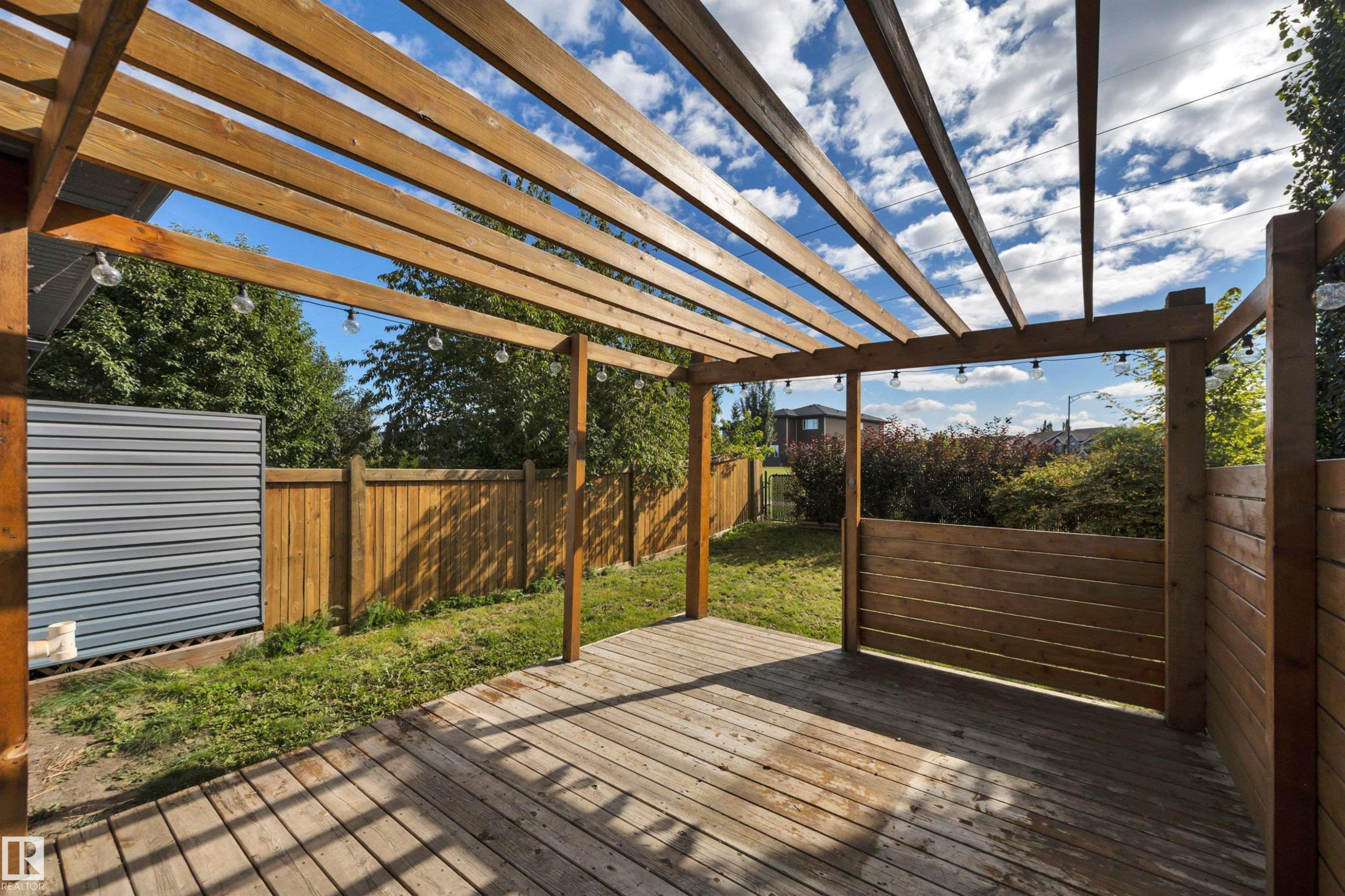 Wood pergola structure over a spacious deck with perimeter fencing and a grass area - 12903 205 Street Nw, Edmonton, AB