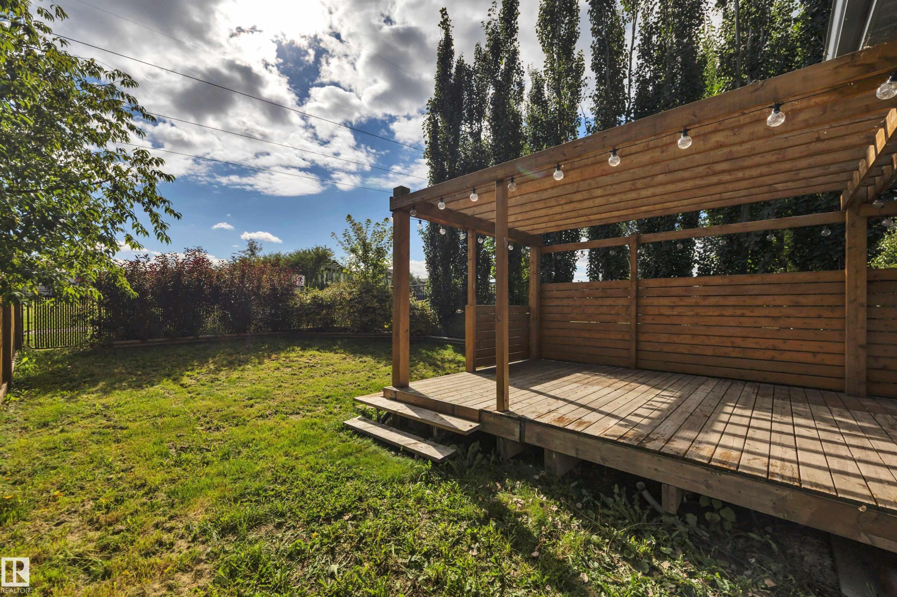 Expansive backyard featuring a wood deck with a pergola, integrated string lighting, and wood privacy screens - 12903 205 Street Nw, Edmonton, AB