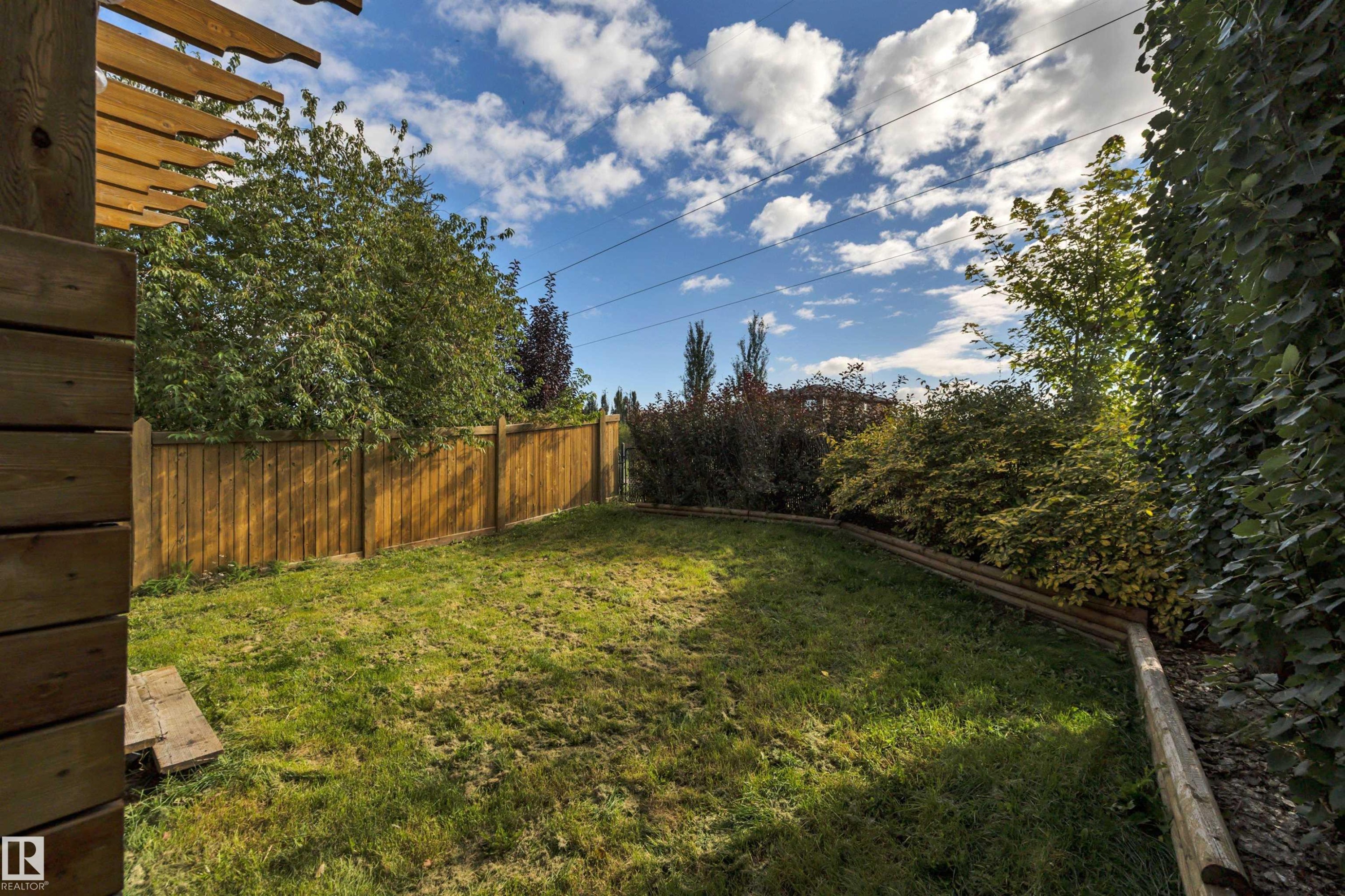 Expansive outdoor space featuring a manicured lawn, wood fencing, and mature perimeter landscaping - 12903 205 Street Nw, Edmonton, AB