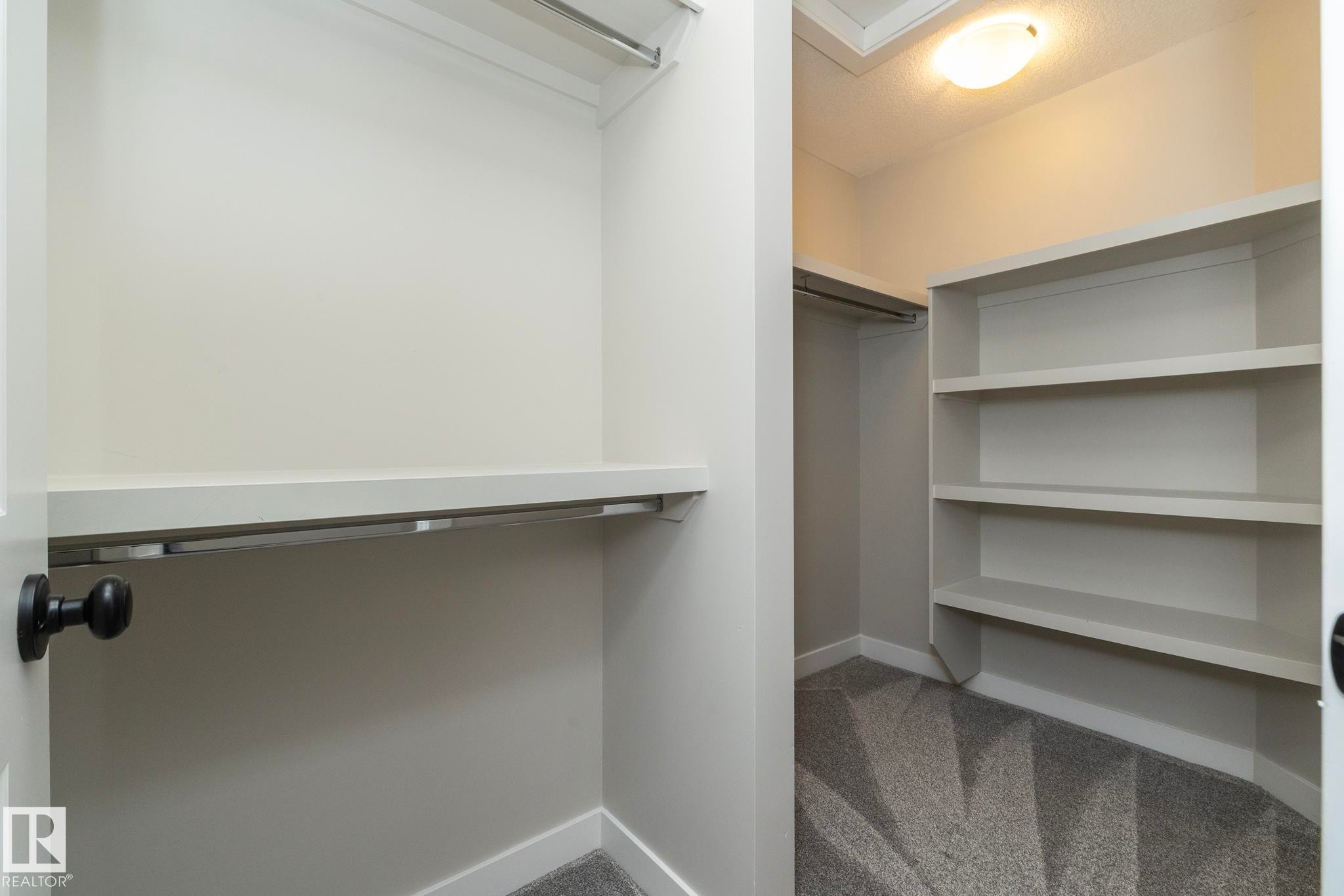 Walk-in closet featuring built-in shelving, hanging rods, and patterned carpet flooring - 53/55 Michigan Street, Devon, AB
