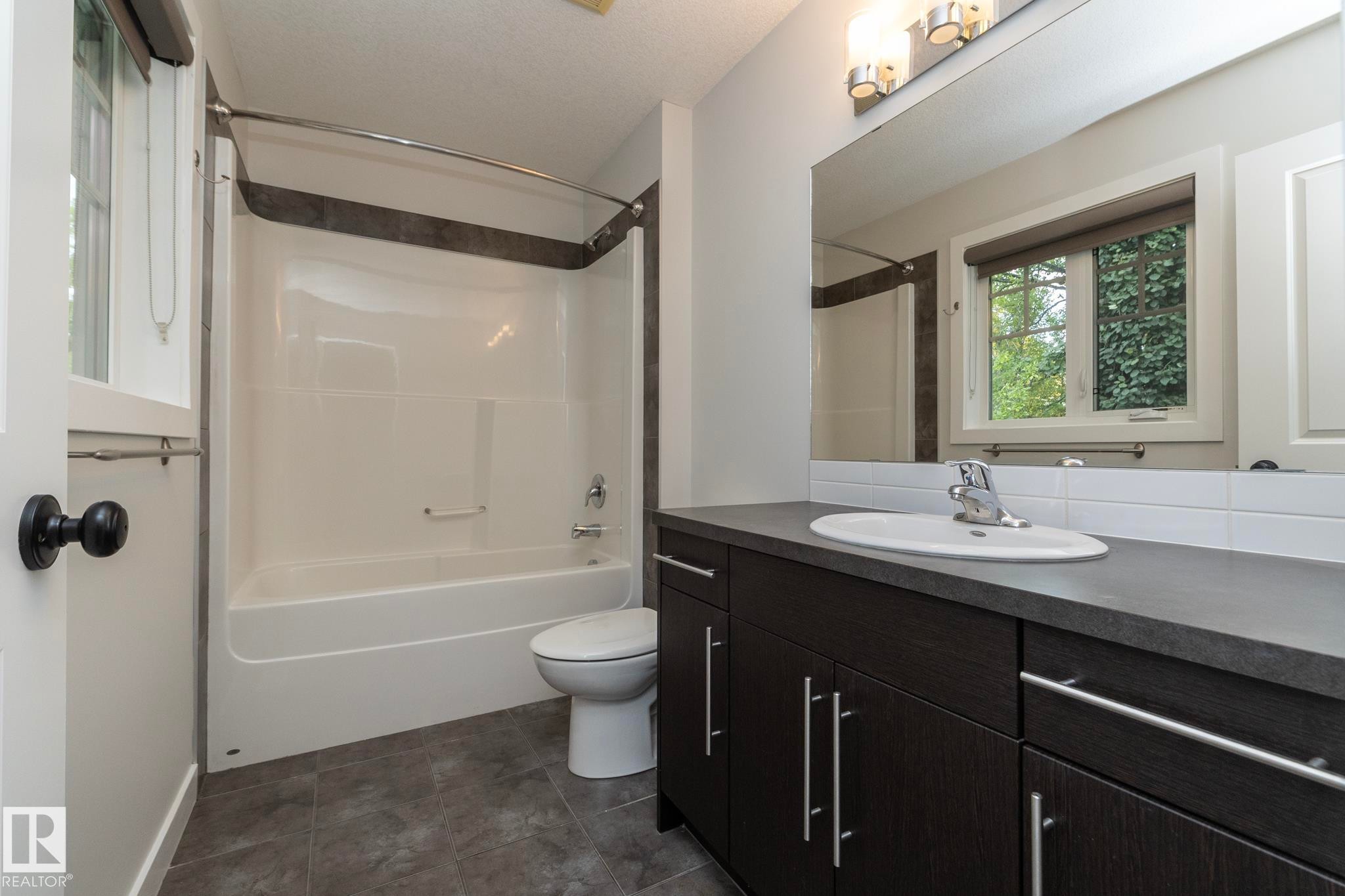 Dark wood-finish vanity with a built-in sink and chrome faucet - 53/55 Michigan Street, Devon, AB