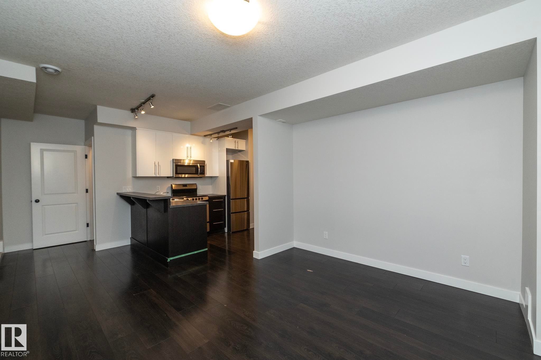 Dark wood-finish flooring throughout, complemented by light-toned walls - 53/55 Michigan Street, Devon, AB