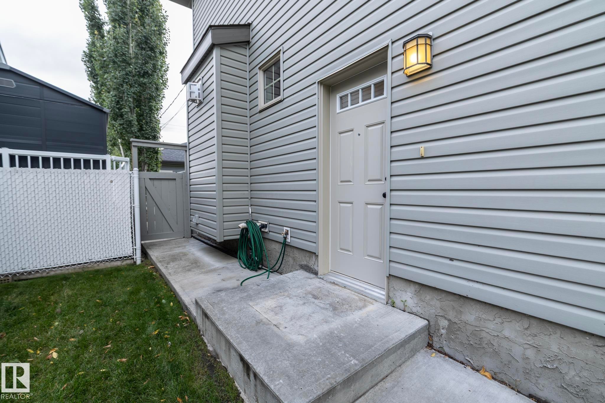 Light grey siding with a paneled exterior door and transom window - 53/55 Michigan Street, Devon, AB