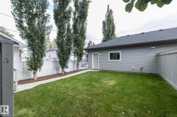 Gable roof with asphalt shingles, vinyl siding, fenced yard, concrete pathway, and mature trees - 