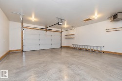 Attached garage with an overhead door, automatic opener, concrete flooring, and built-in wall shelving - 