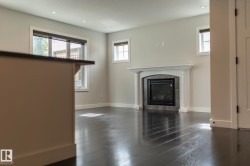Dark-toned wood-finish flooring, recessed lighting, and a fireplace with a stone surround and ornate mantel - 