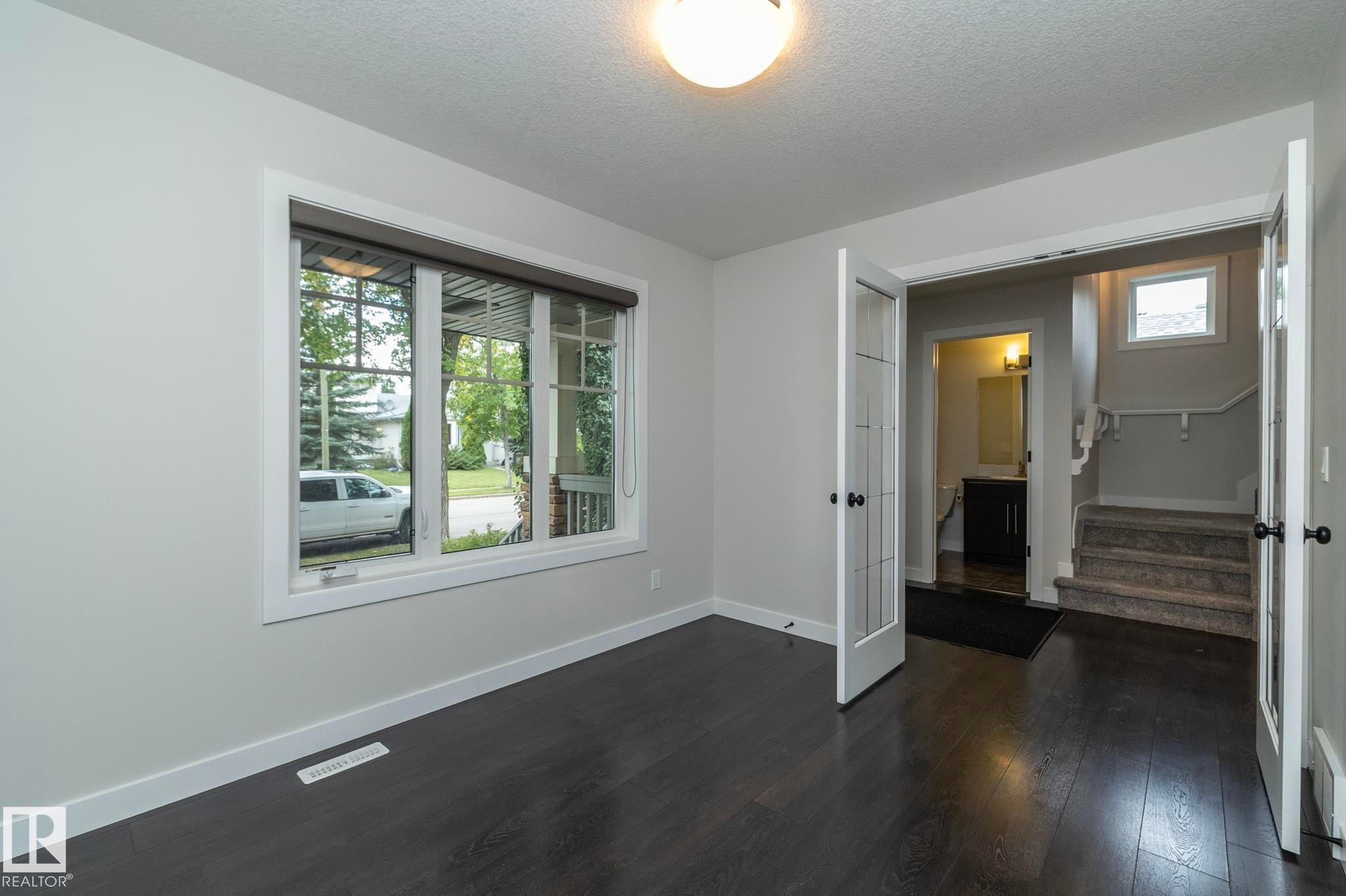 Dark wood-finish flooring, white trim, and a window with blinds - 53/55 Michigan Street, Devon, AB