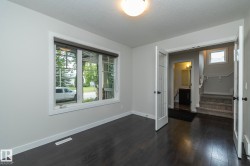 Dark wood-finish flooring, white trim, and a window with blinds - 