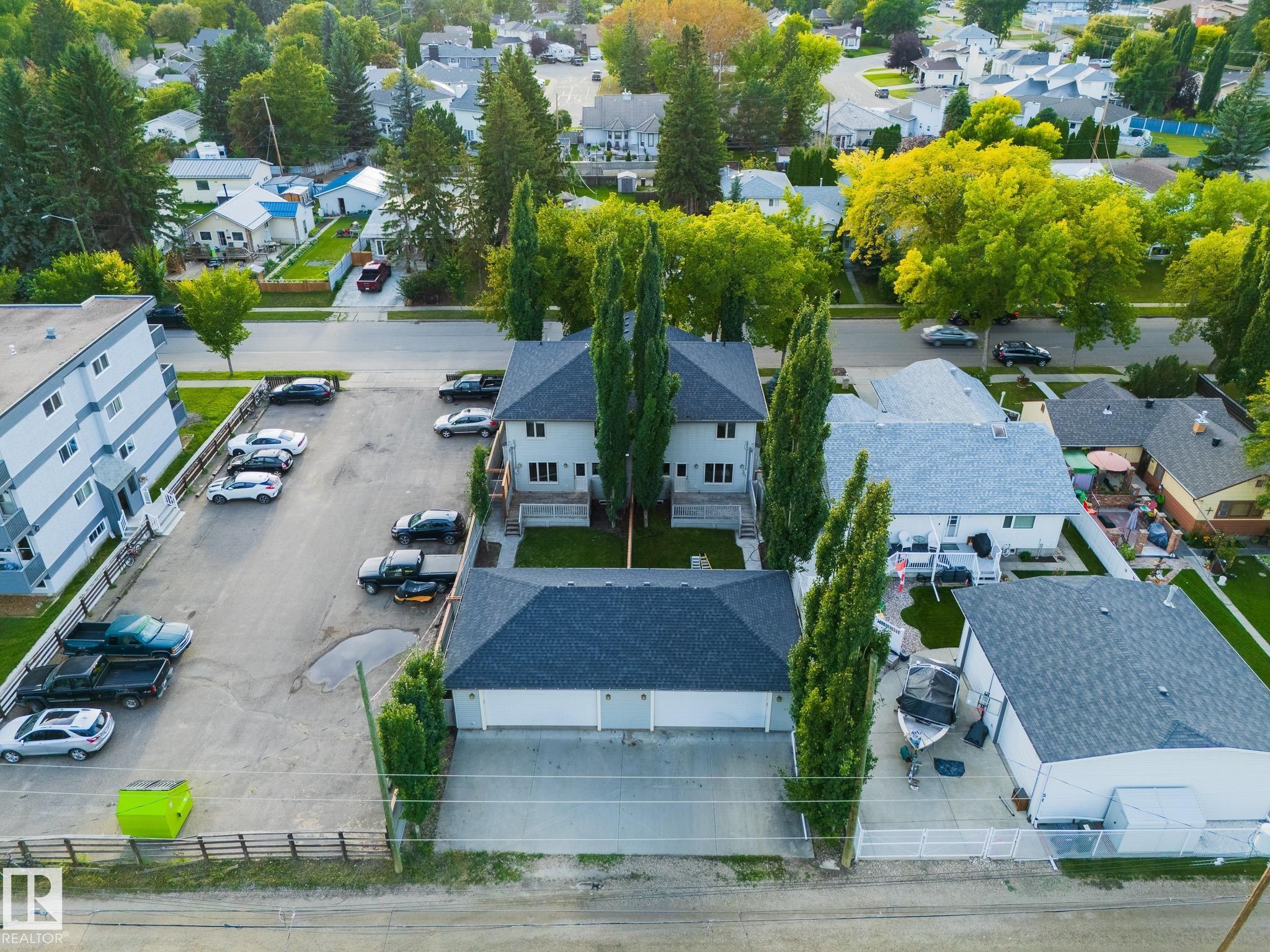Duplex property with a detached two-car garage, mature landscaping, and a paved parking area - 53/55 Michigan Street, Devon, AB