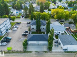 Duplex property with a detached two-car garage, mature landscaping, and a paved parking area - 
